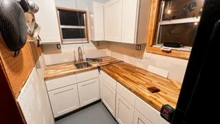 White kitchen cabinets with natural wood countertops and updated fixtures