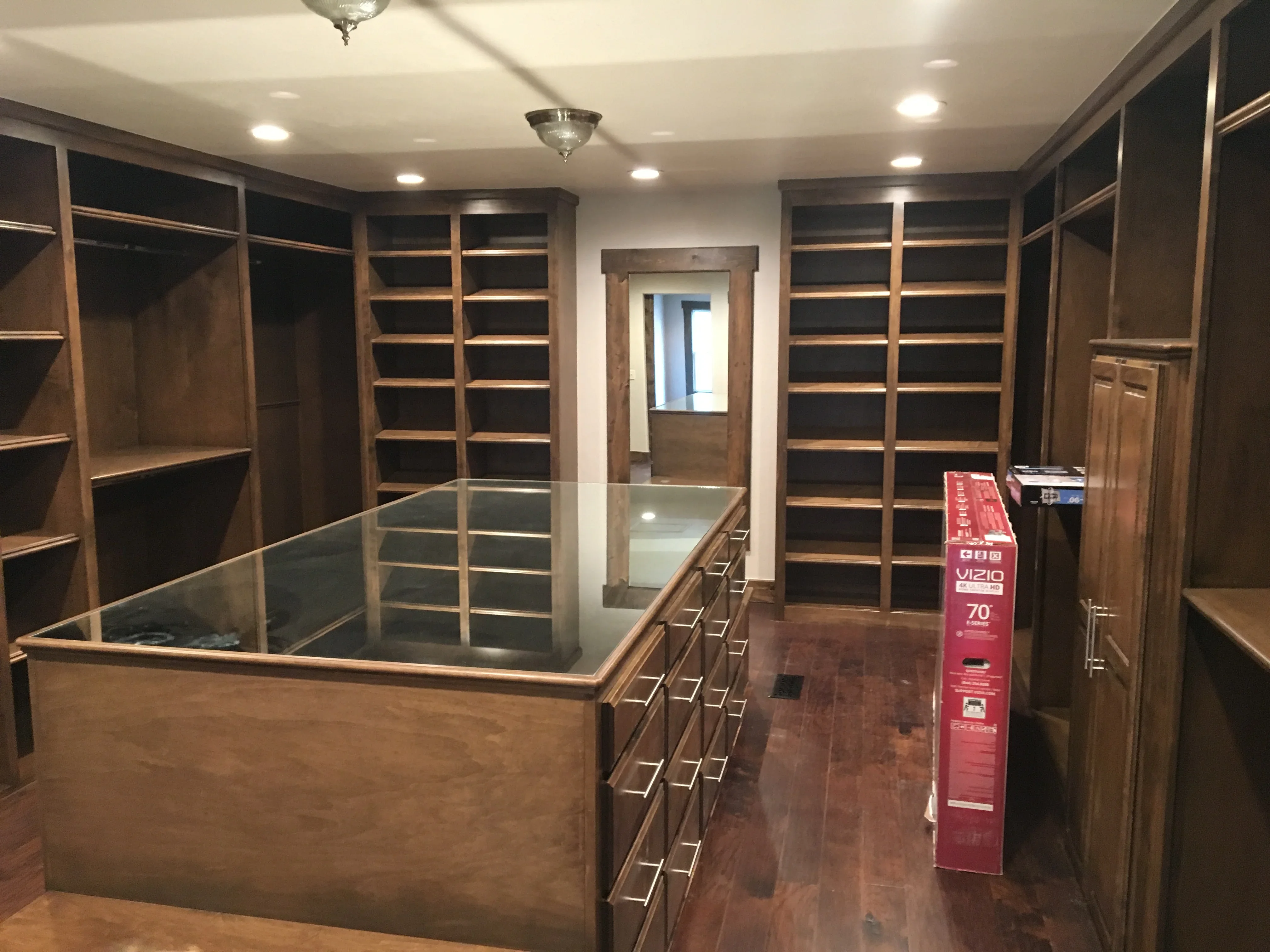 Custom walk-in closet with dark wood cabinetry, glass display cases, and recessed lighting
