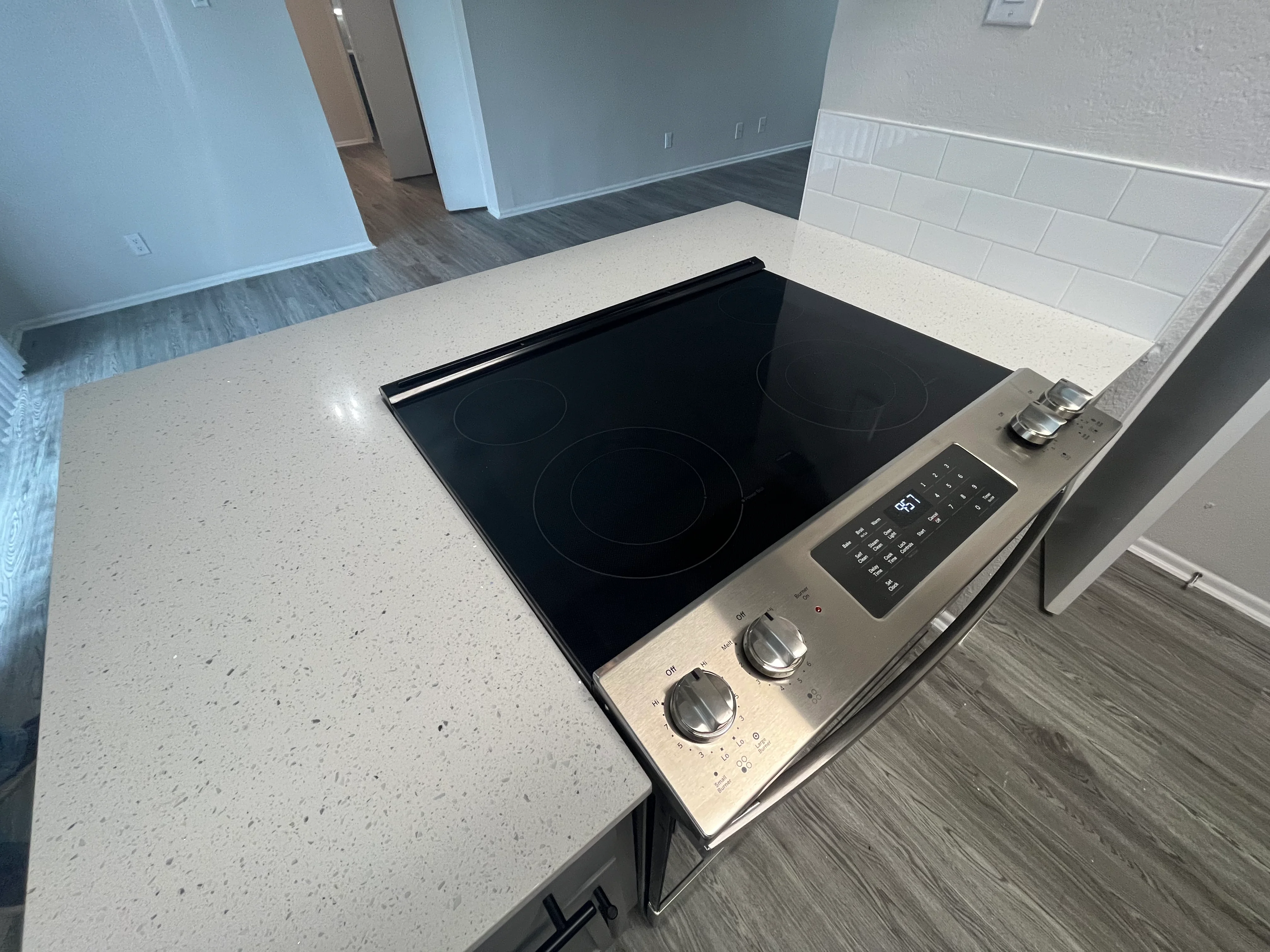 Modern kitchen with quartz counters, white backsplash, and stainless steel electric cooktop