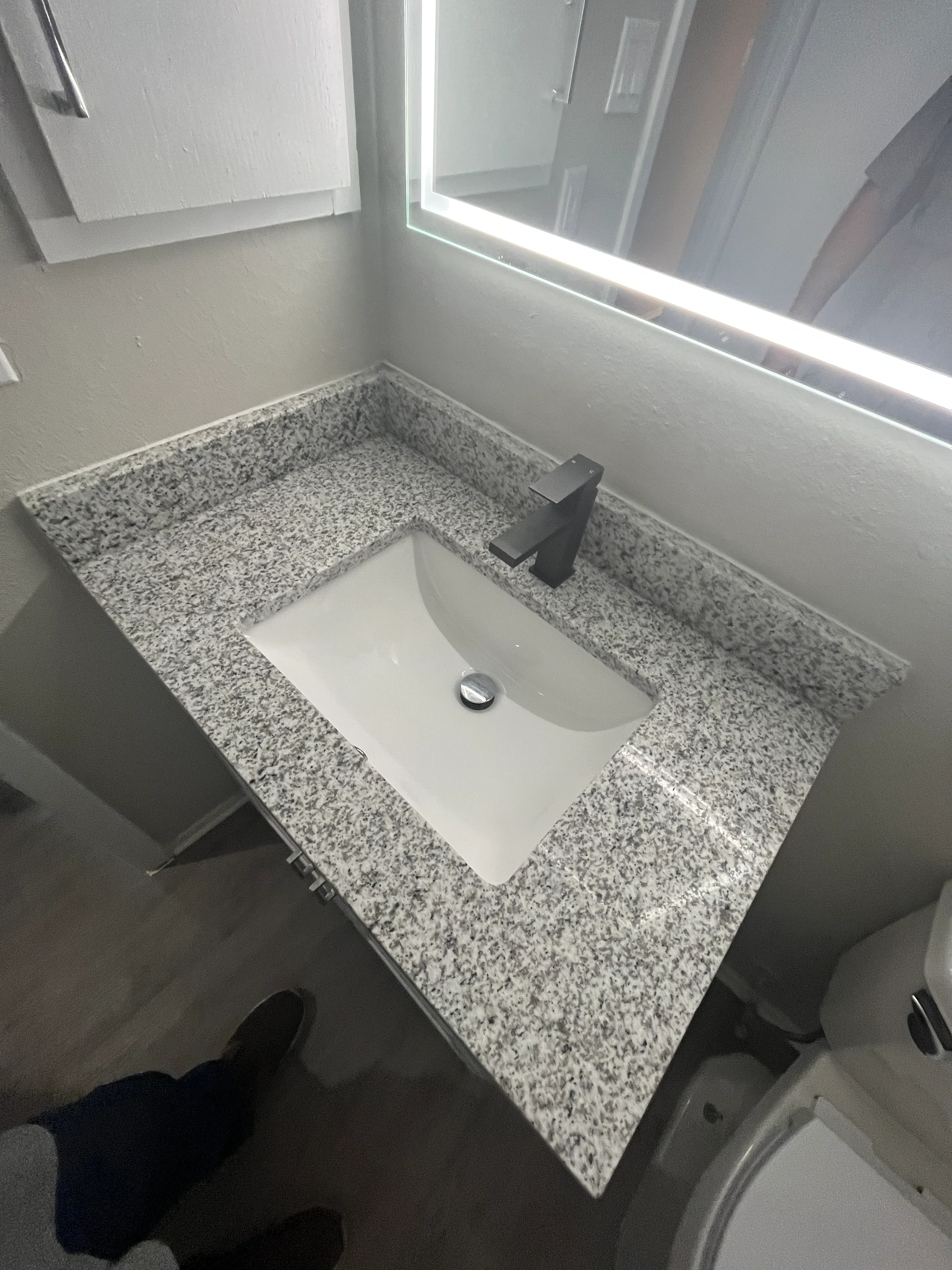 Granite bathroom vanity with white undermount sink and black faucet in bright bathroom