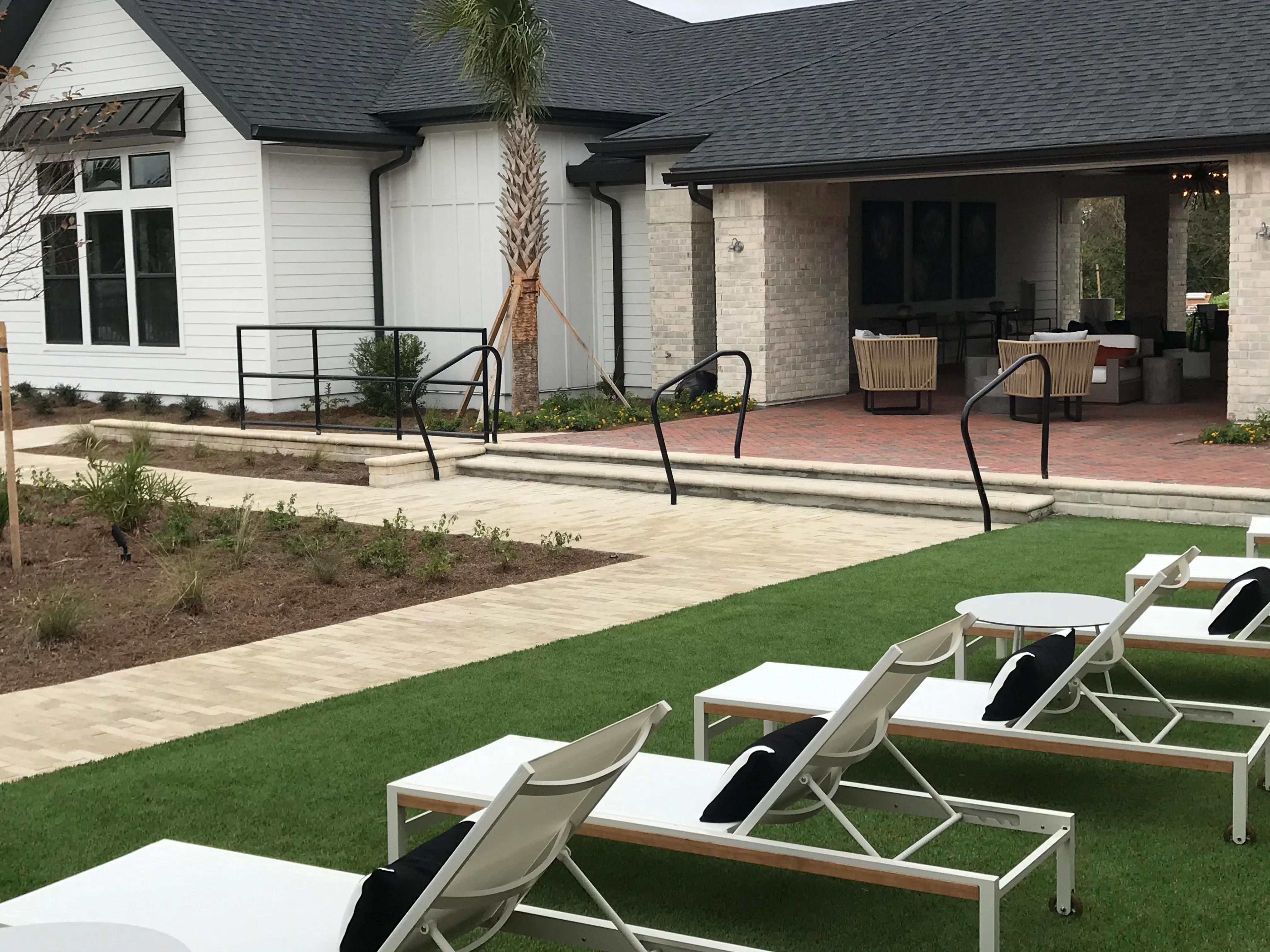 Modern backyard with paver patio, synthetic turf, lounge chairs, and stone patio cover