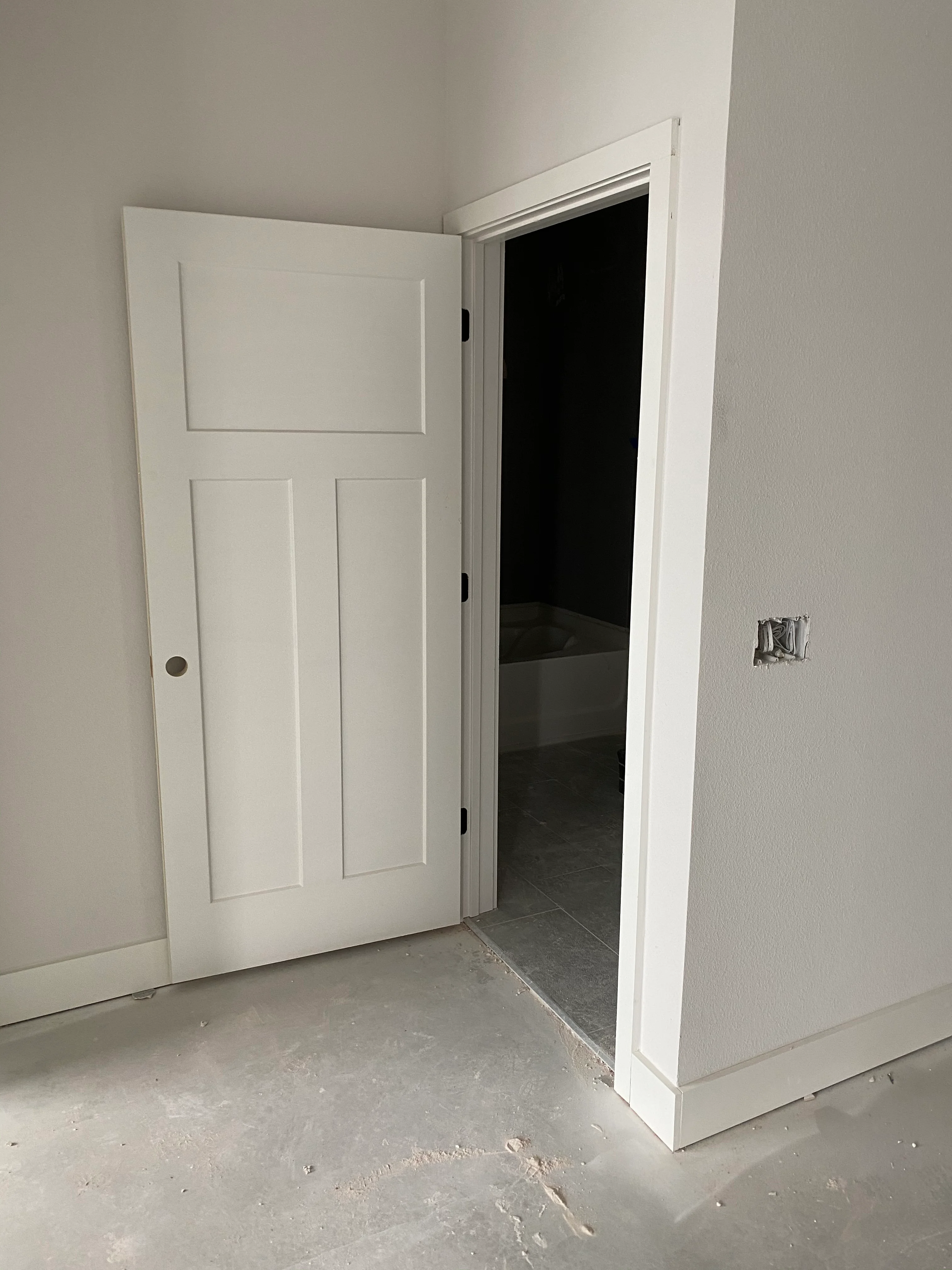 White three-panel interior door with trim installed in new construction room