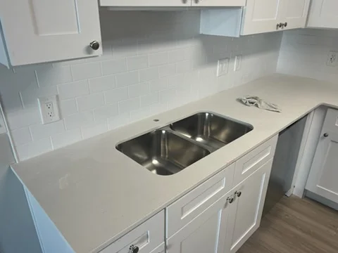 White quartz kitchen countertop with stainless steel double sink and subway tile backsplash