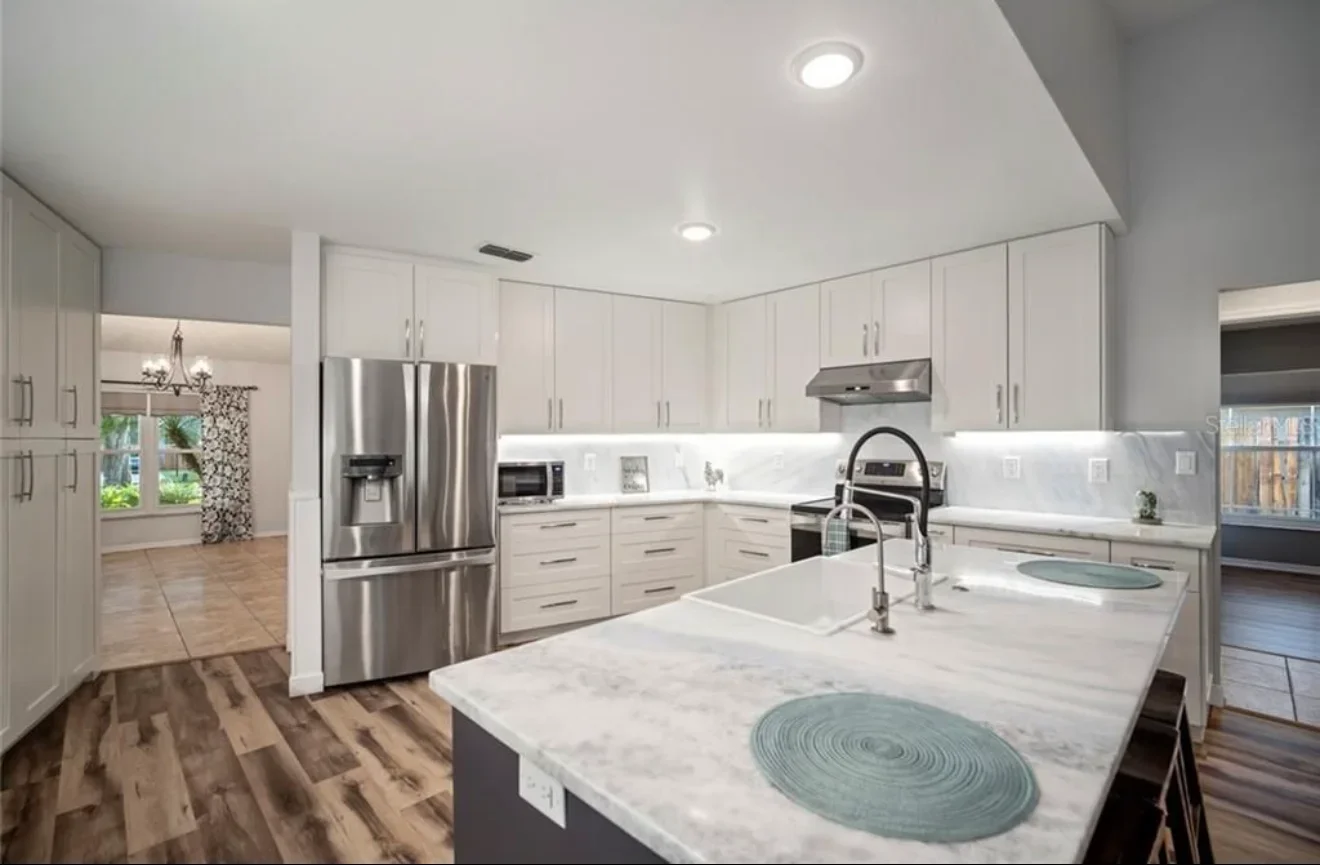 Modern kitchen with white cabinets, marble countertops, stainless steel appliances, and dual islands