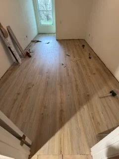 Newly installed hardwood flooring with medium-tone wood planks in staggered pattern