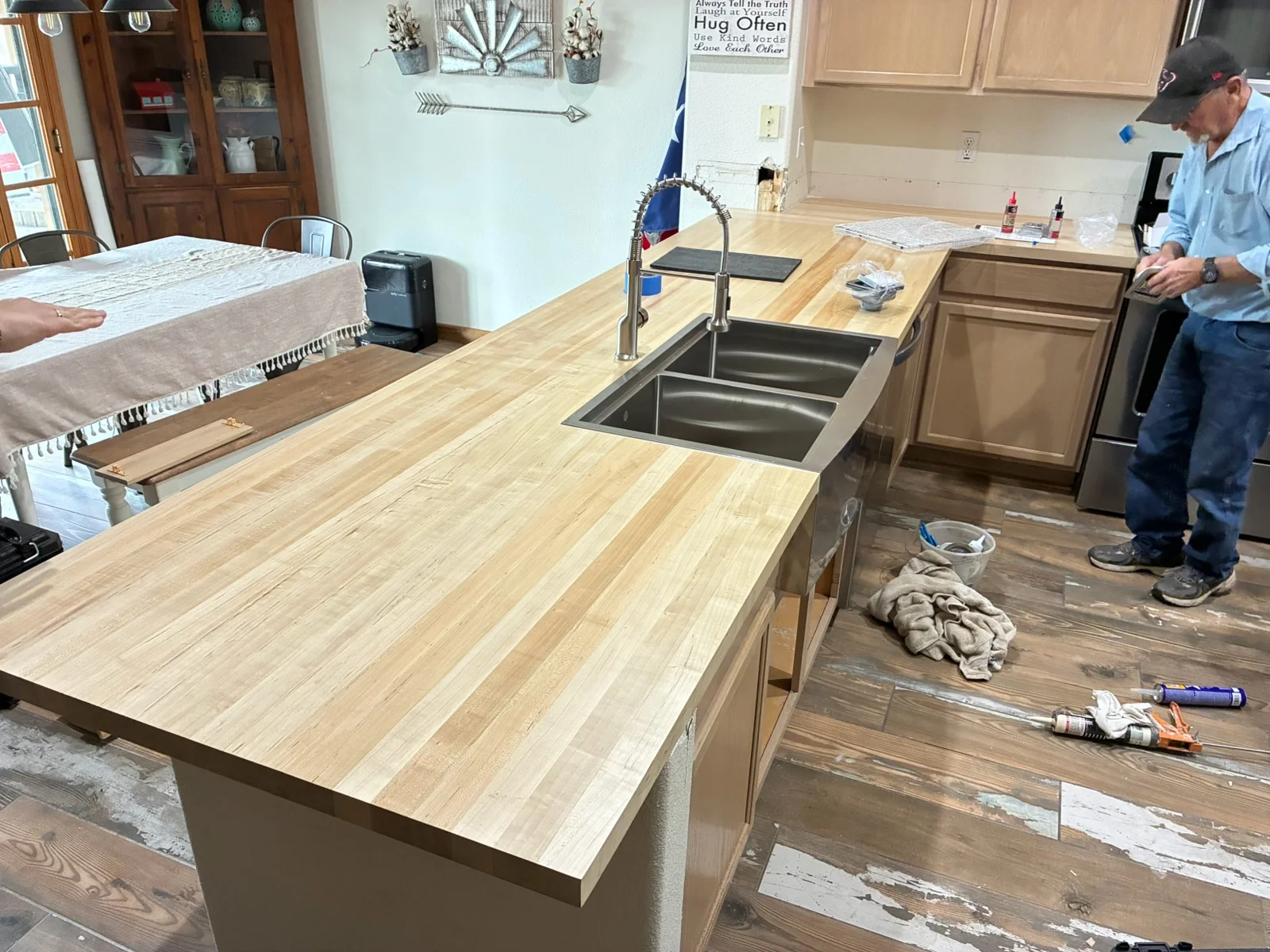 Kitchen remodel with light oak wood countertops, stainless steel sink, and new cabinetry installation in progress