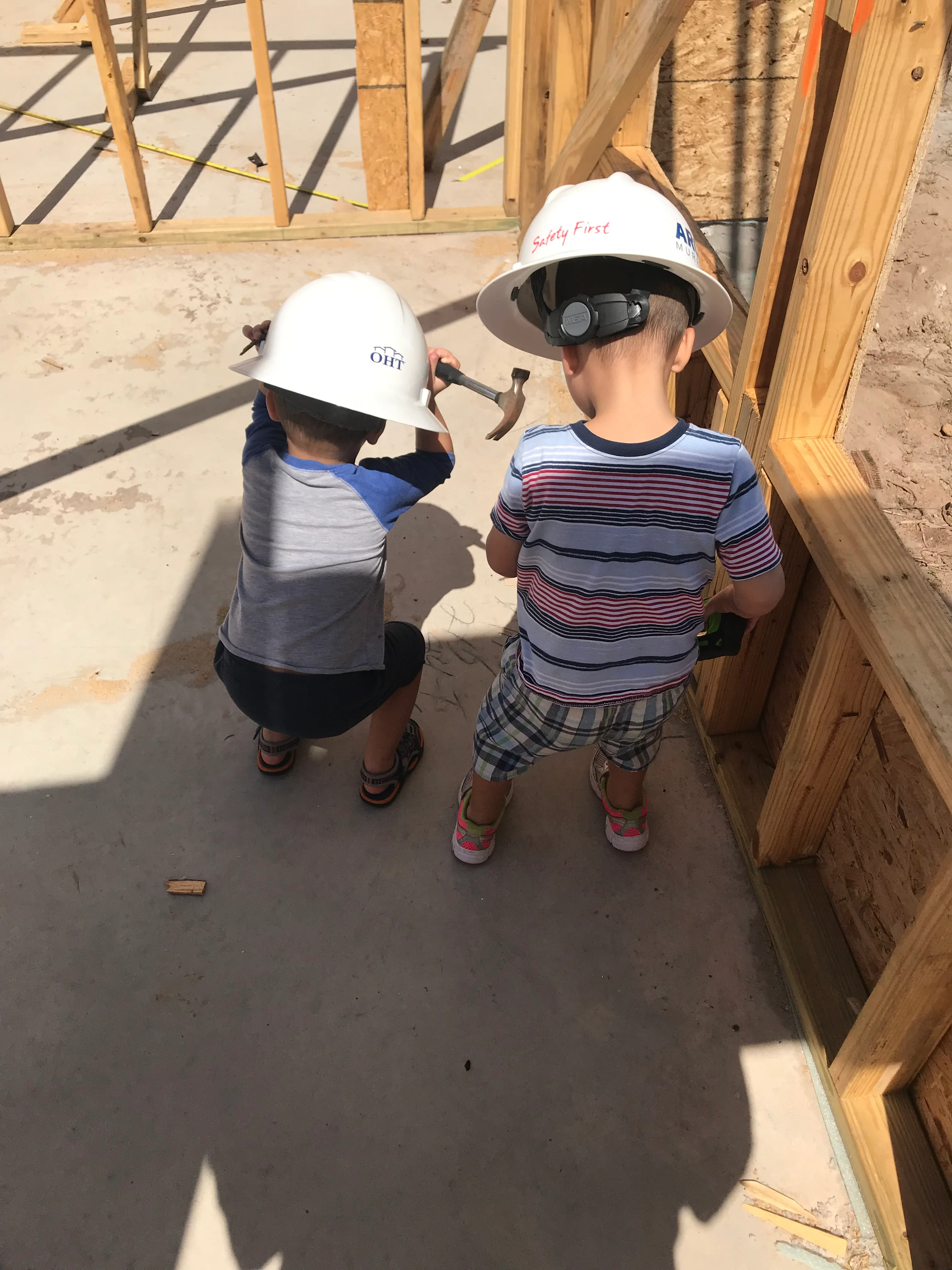 Construction workers in hard hats inspecting wooden framing on residential foundation