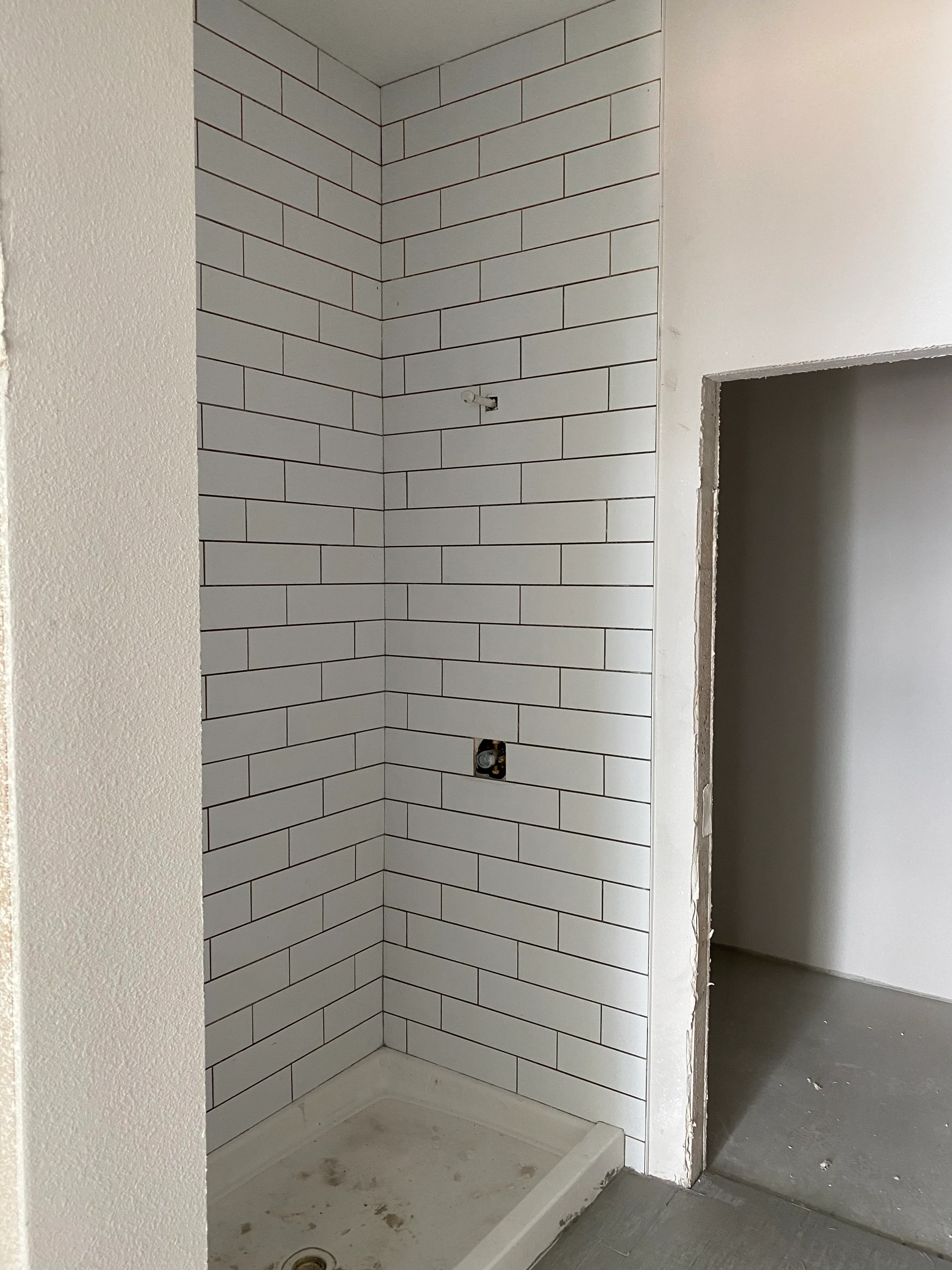 Light gray subway tile shower with dark grout lines in running bond pattern