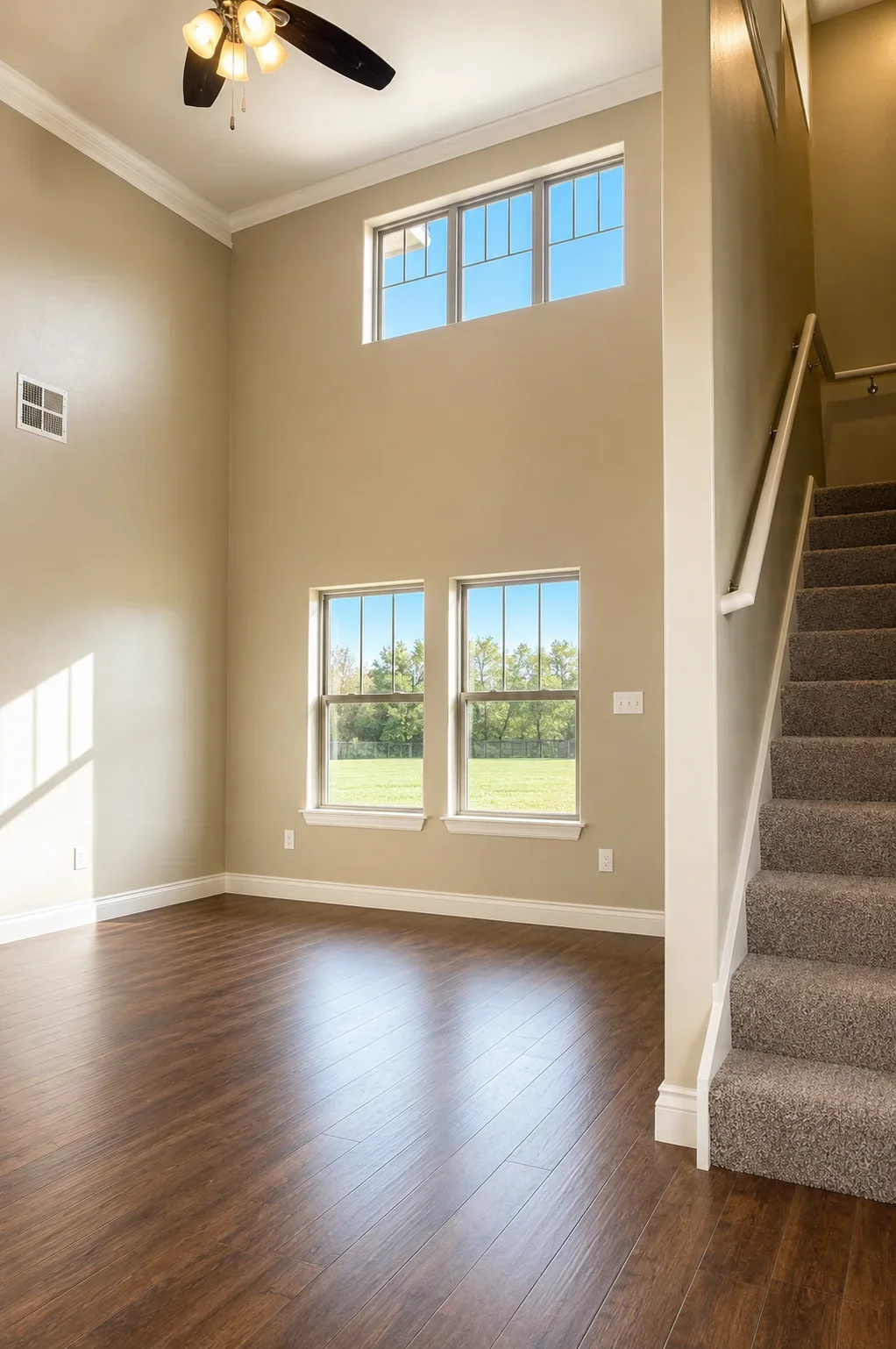 Two-story great room with hardwood floors, large windows, and white trim