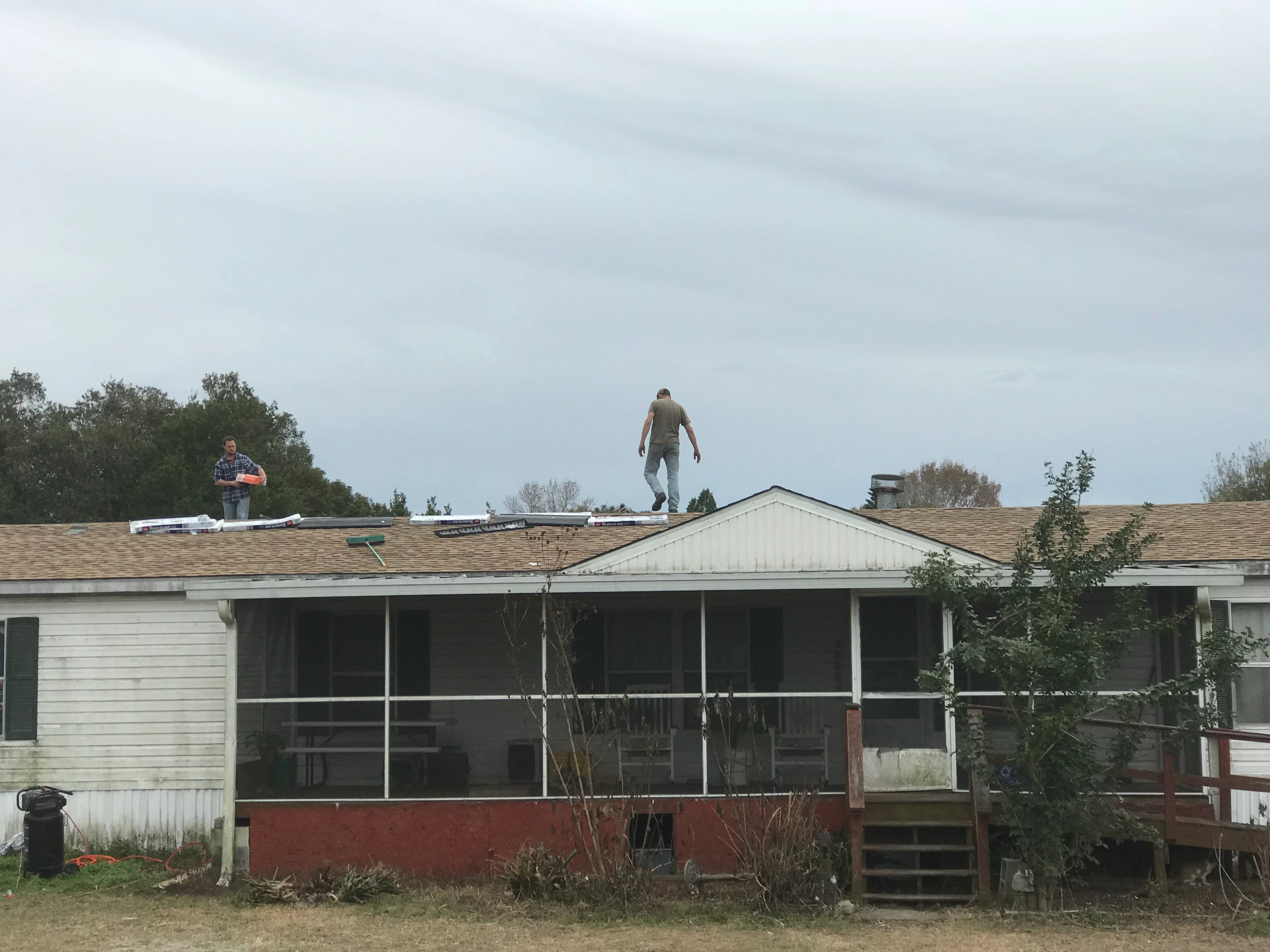 Roofers installing new asphalt shingles on mobile home roof in San Antonio