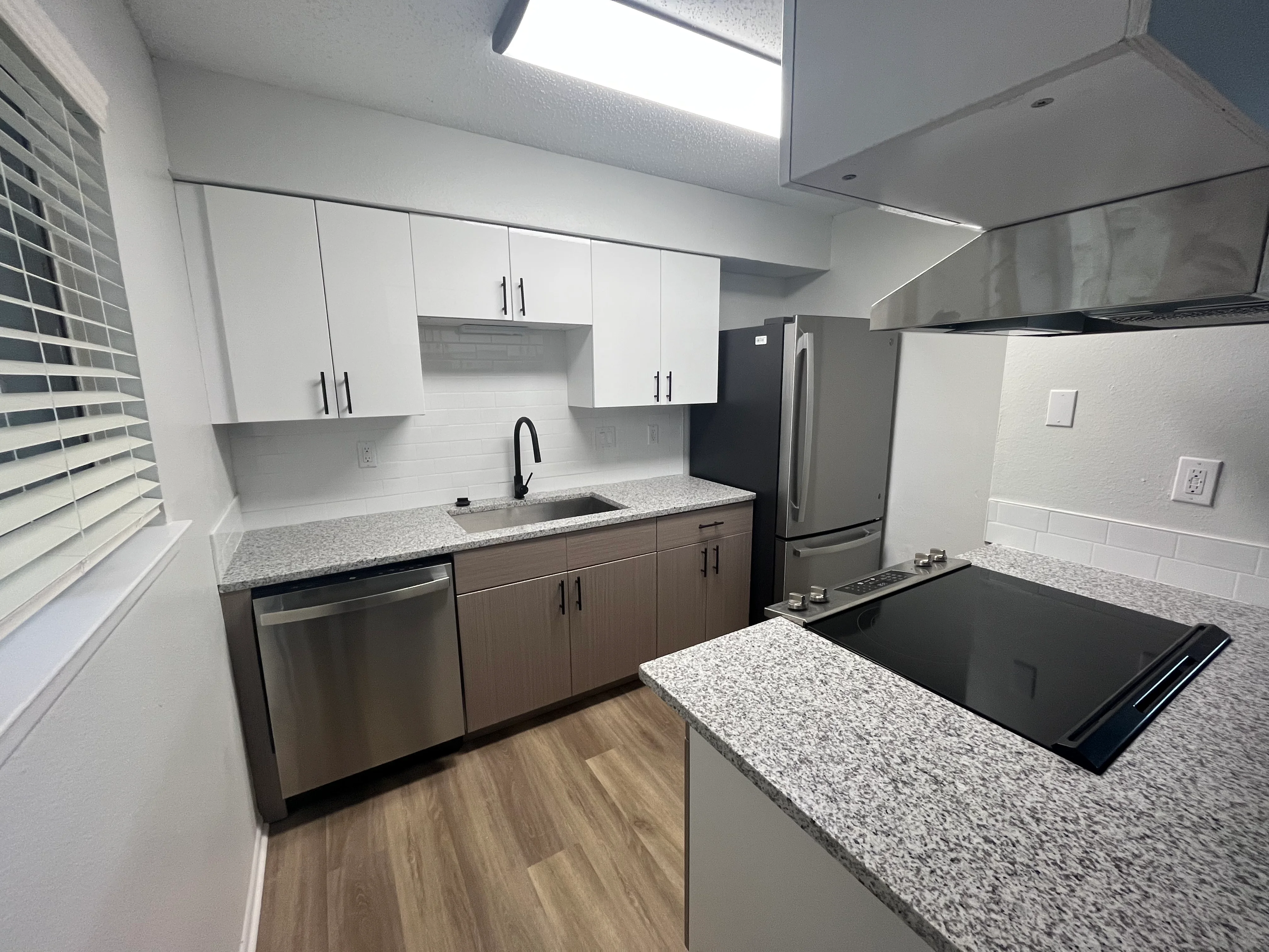 Modern kitchen with white and wood cabinetry, granite counters, and stainless steel appliances