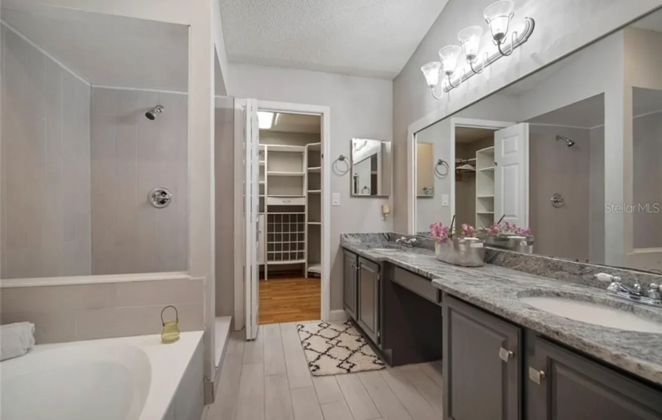 Modern master bathroom with dual vanity, marble counters, and frameless shower