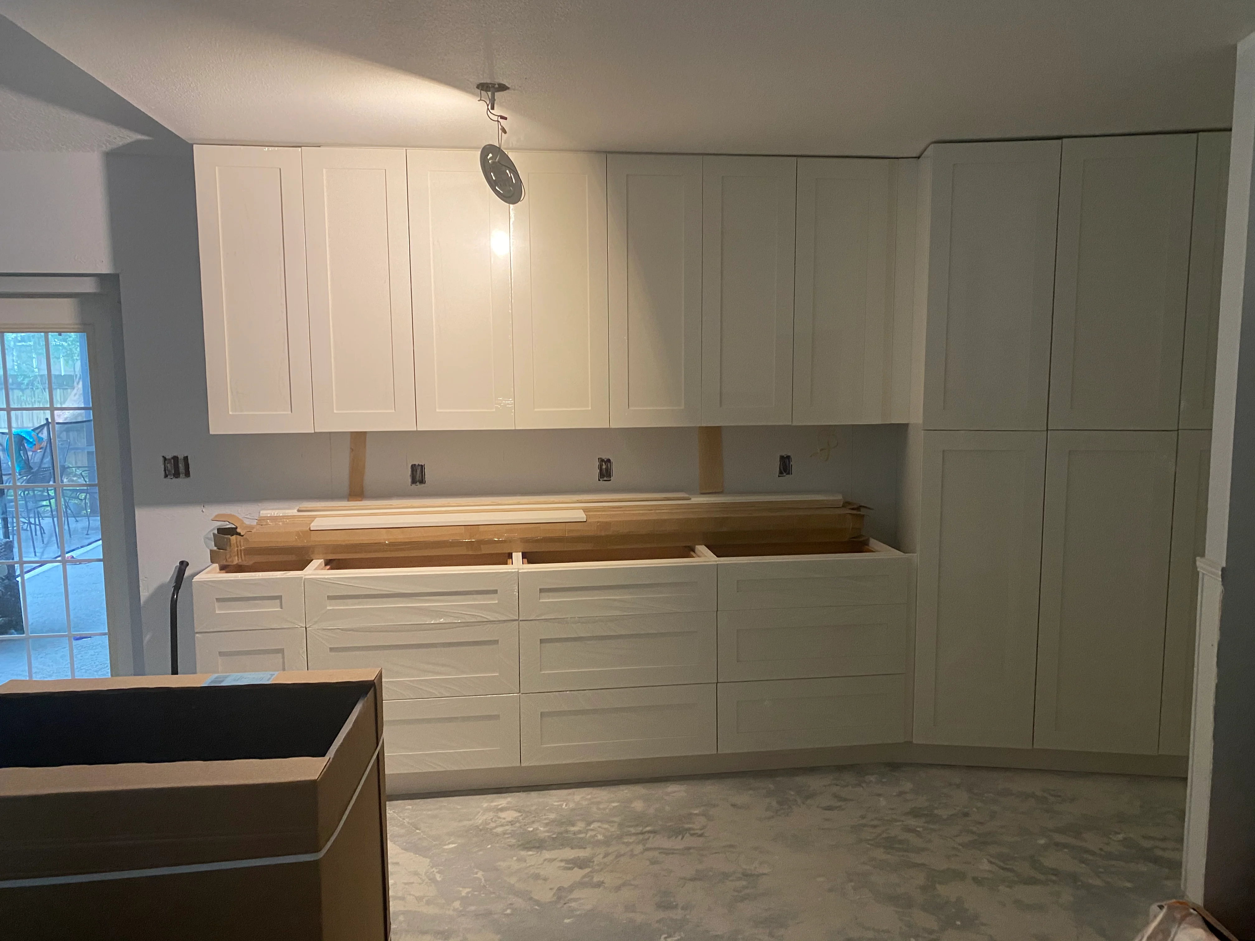 White kitchen cabinets installed with open countertop space and electrical outlets visible