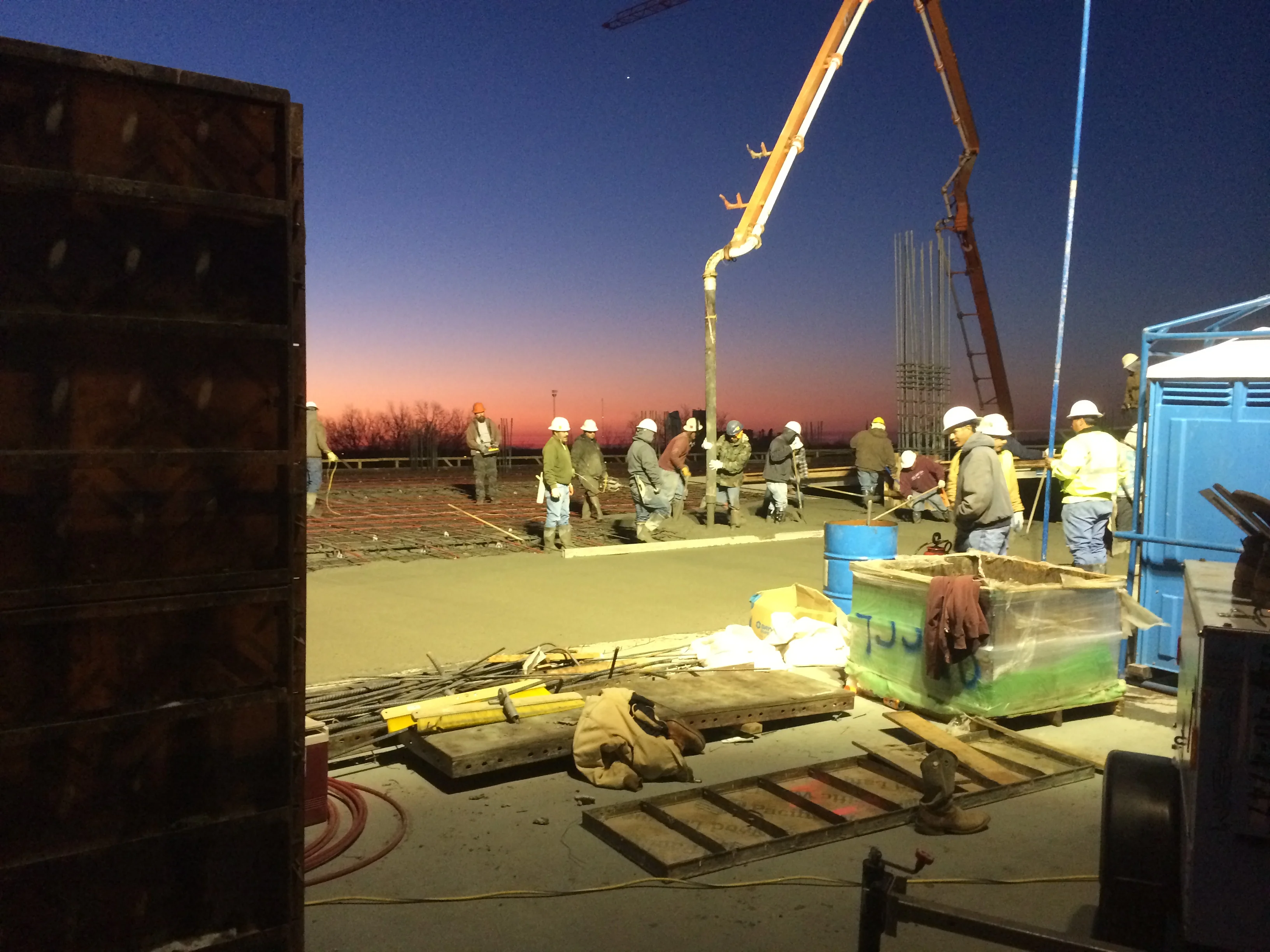 Concrete foundation pour with boom pump truck and construction crew at sunrise