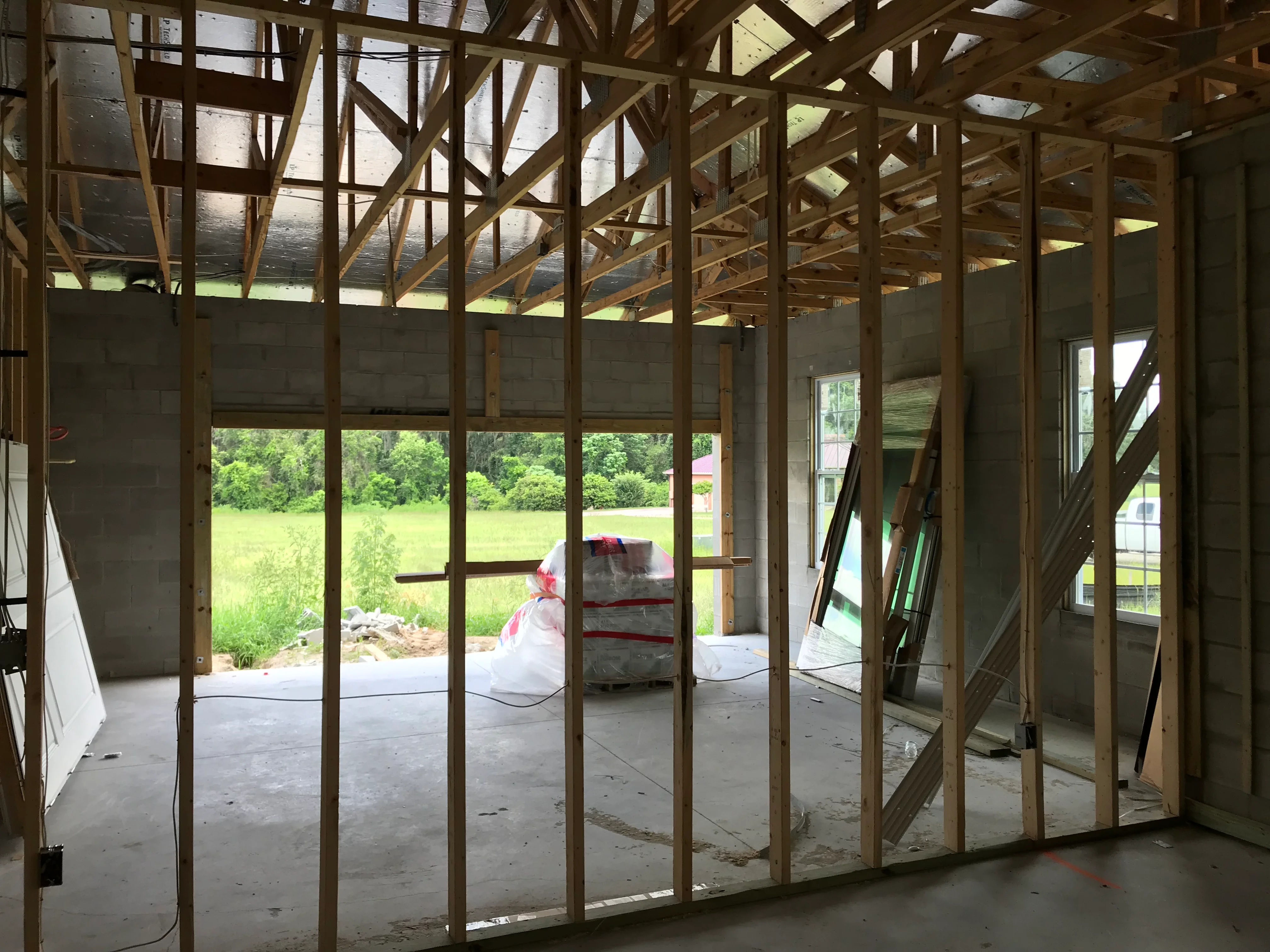 Interior framing of residential addition with wood studs, concrete foundation, and large window openings