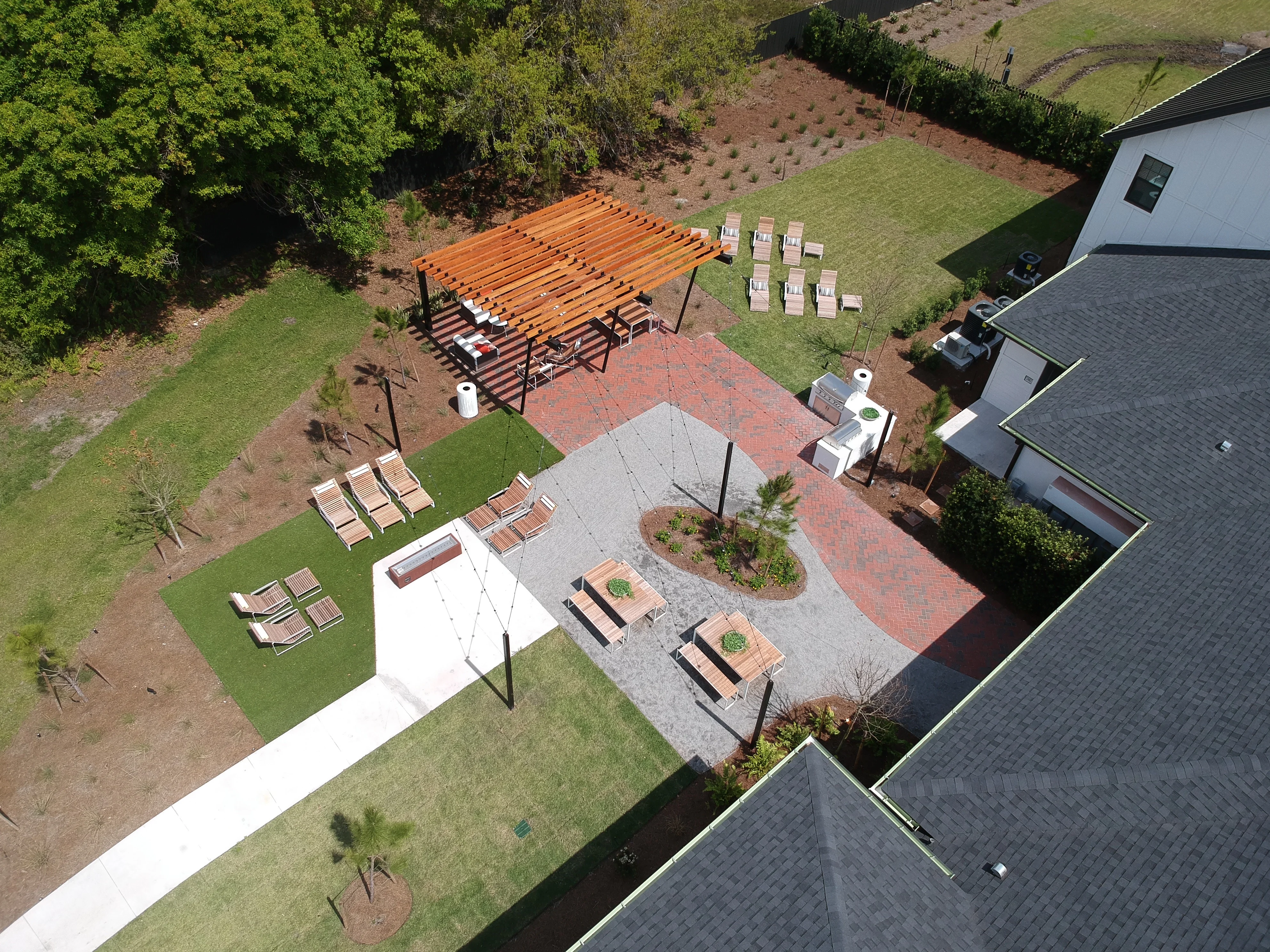 Aerial view of completed residential backyard with two pergolas, brick and paver patio, and landscaping