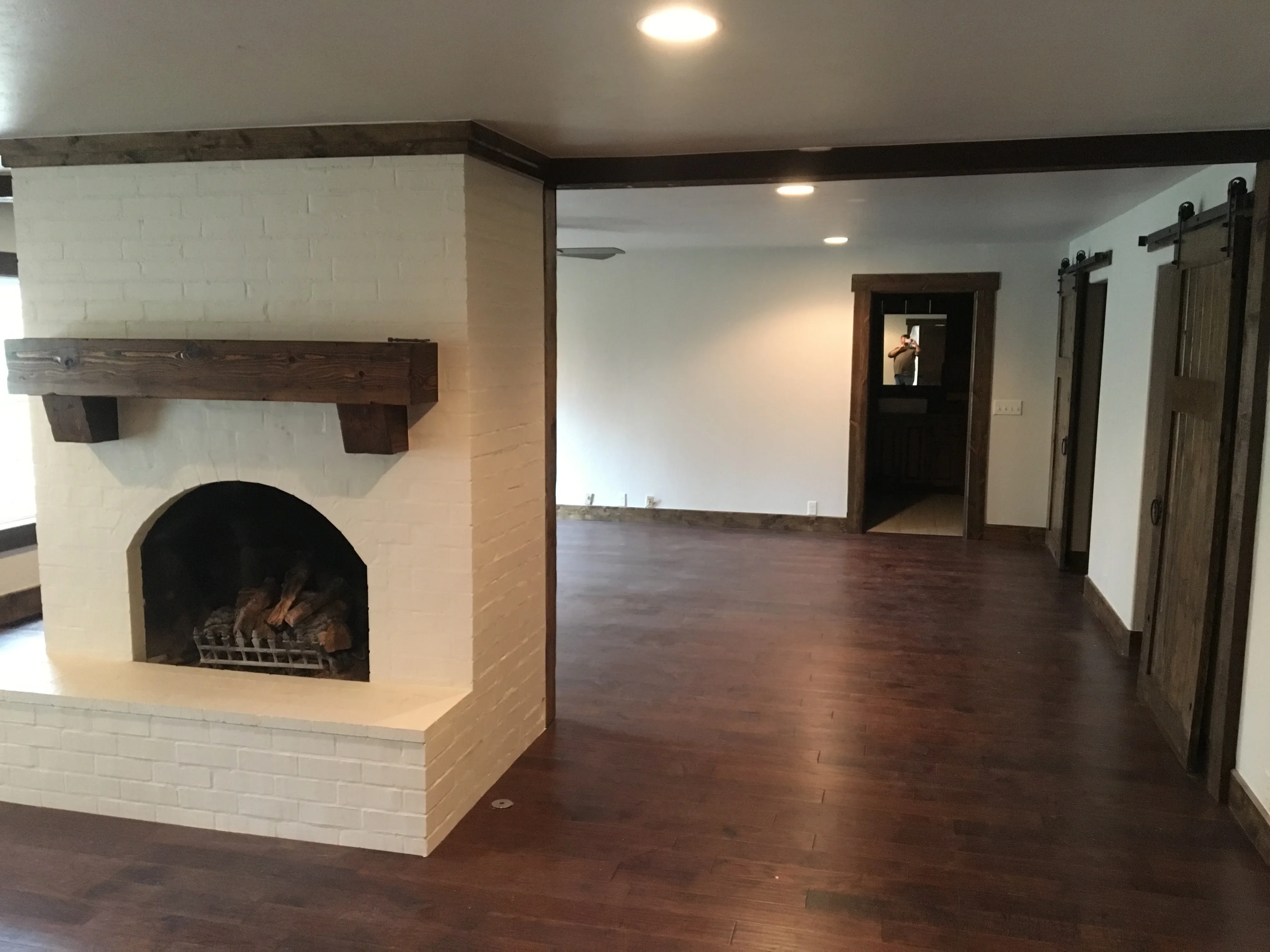 Modern living room with white brick fireplace, dark wood mantel, and hardwood floors