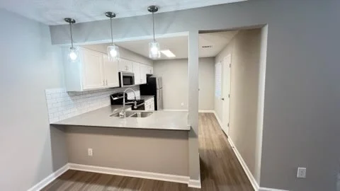 Modern kitchen with white cabinets, subway tile, and pendant lights overlooking dining area