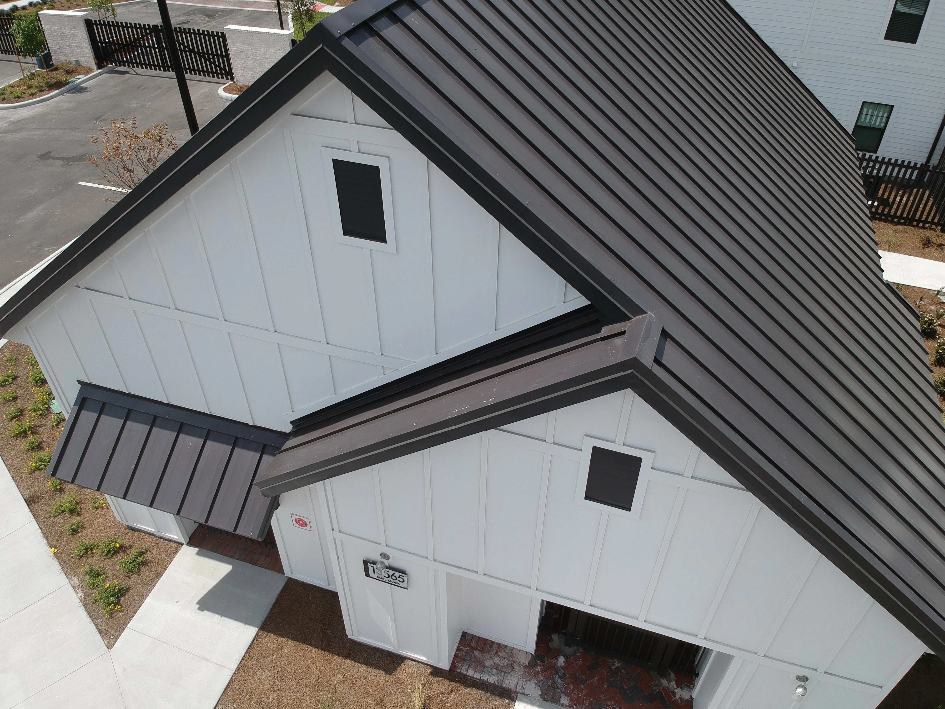Modern home with charcoal metal roof and white siding, aerial view