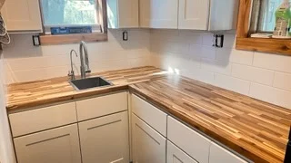 Modern kitchen with white cabinets and natural wood butcher block countertops
