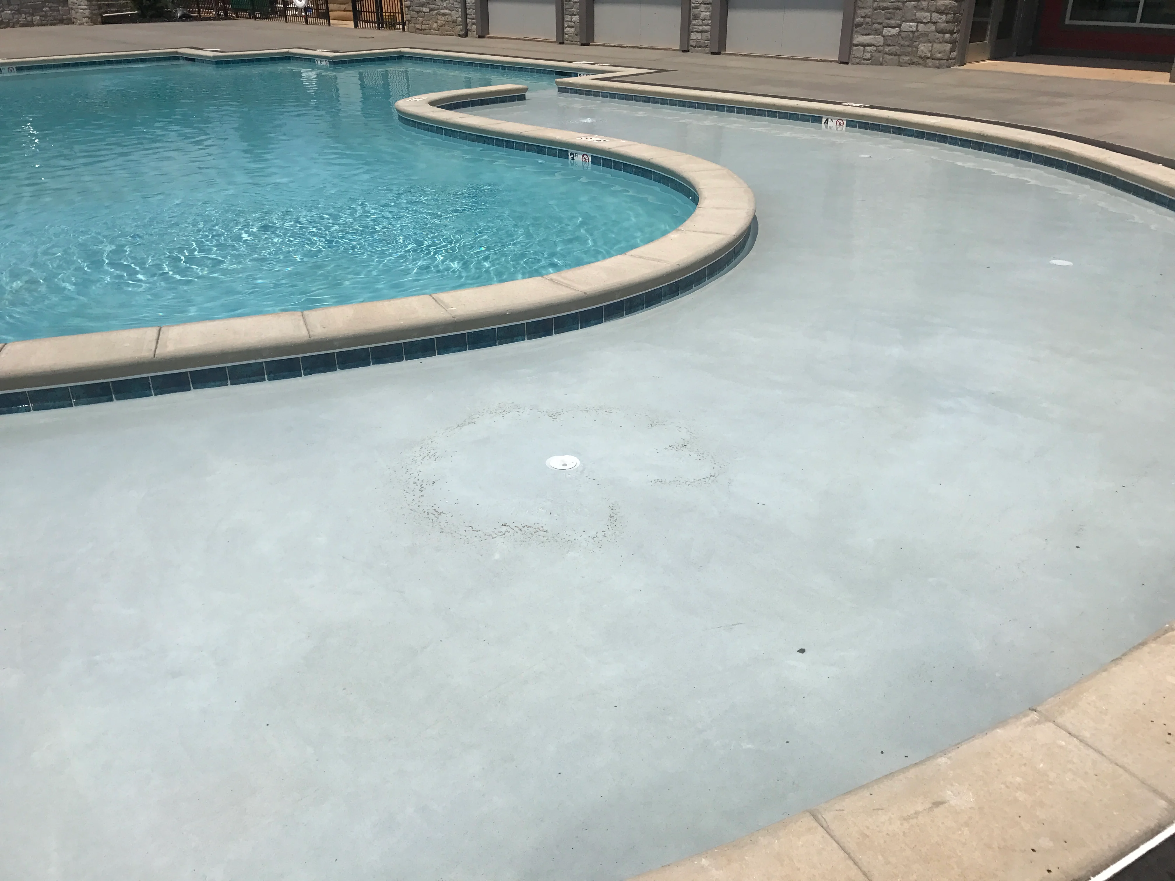 Newly constructed concrete pool deck with spa basin and turquoise swimming pool