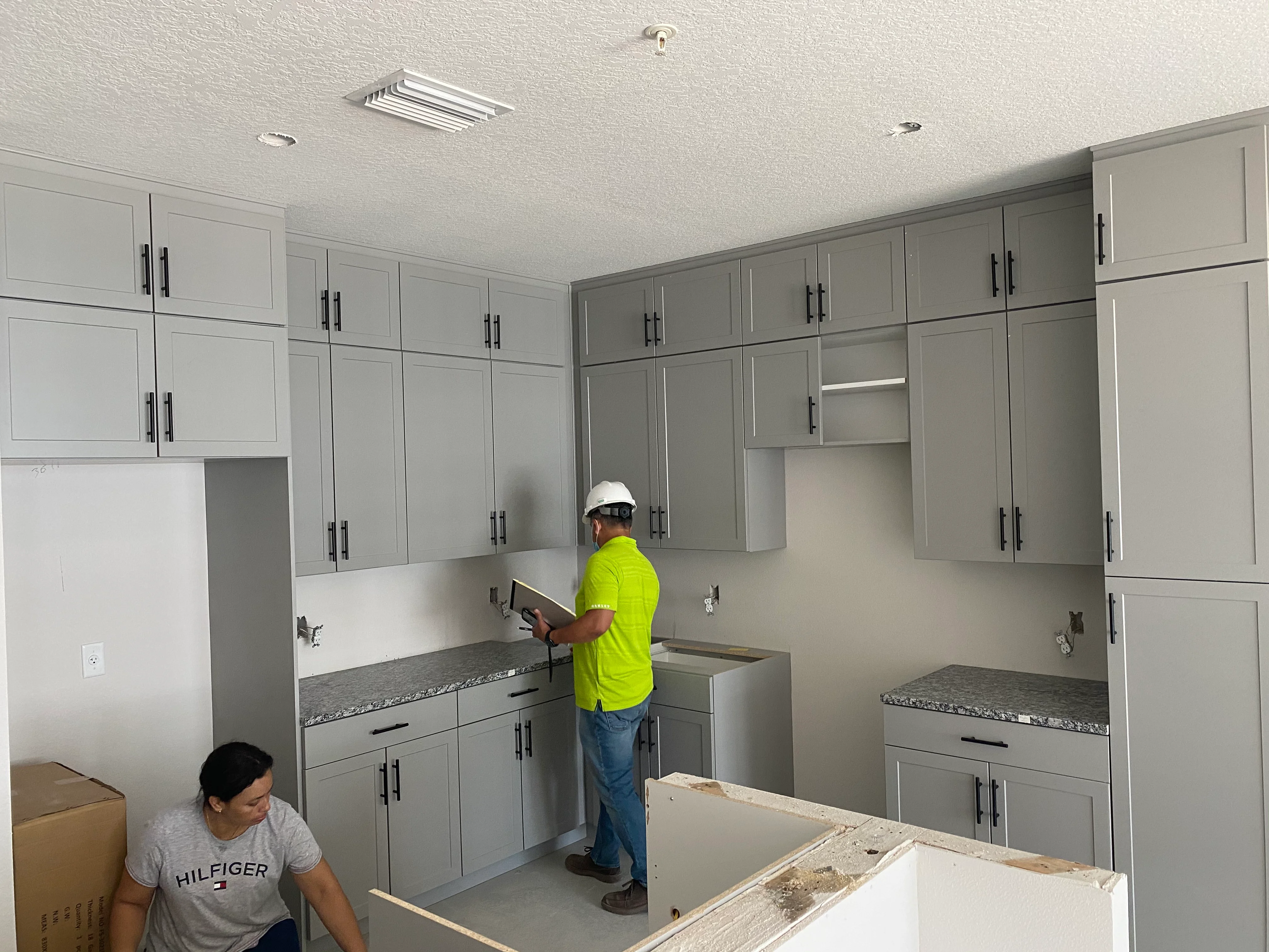 Kitchen remodeling in progress with gray cabinets and granite countertops being installed