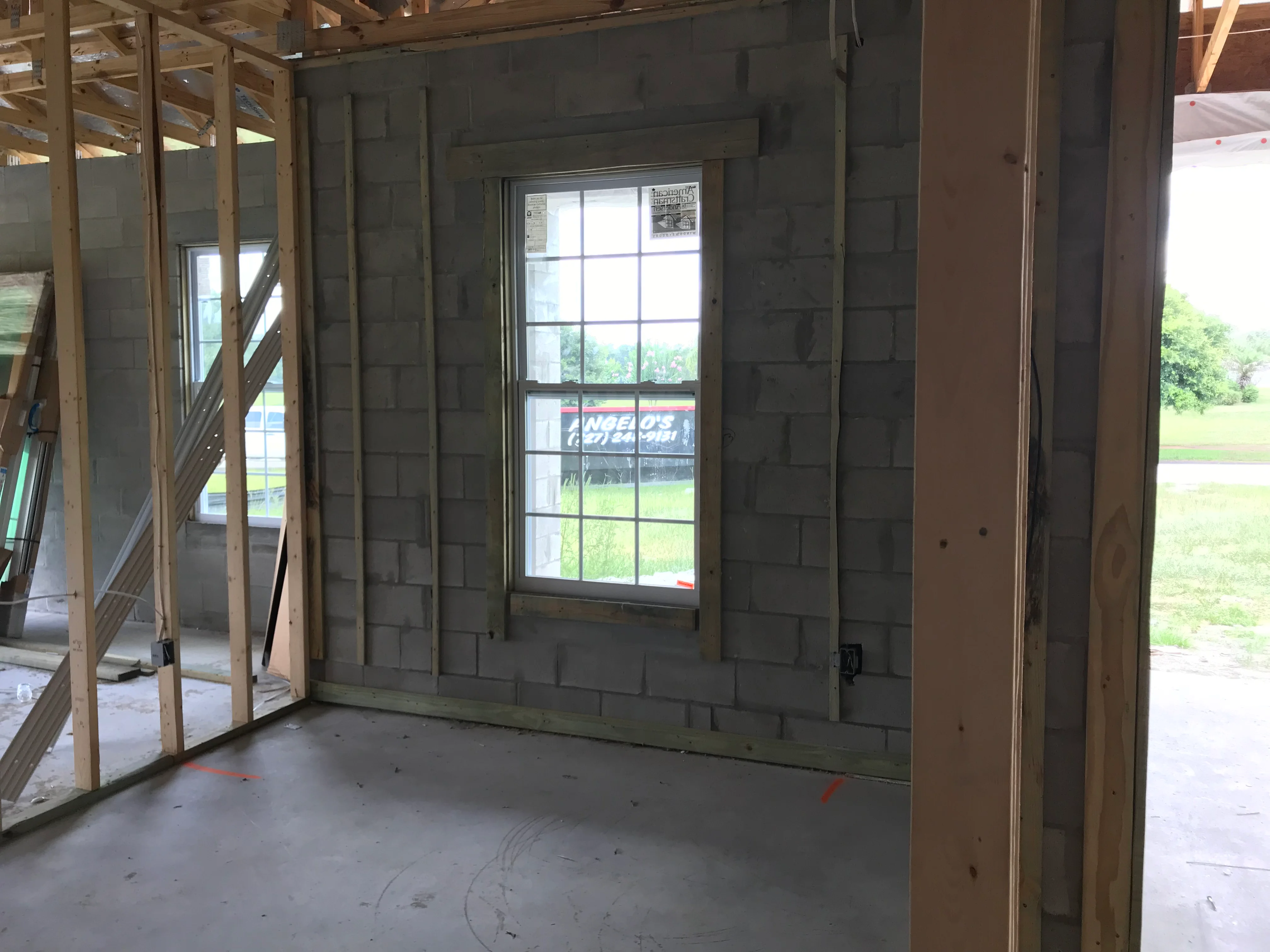 Interior framing with concrete block walls, wood studs, and installed multi-pane window