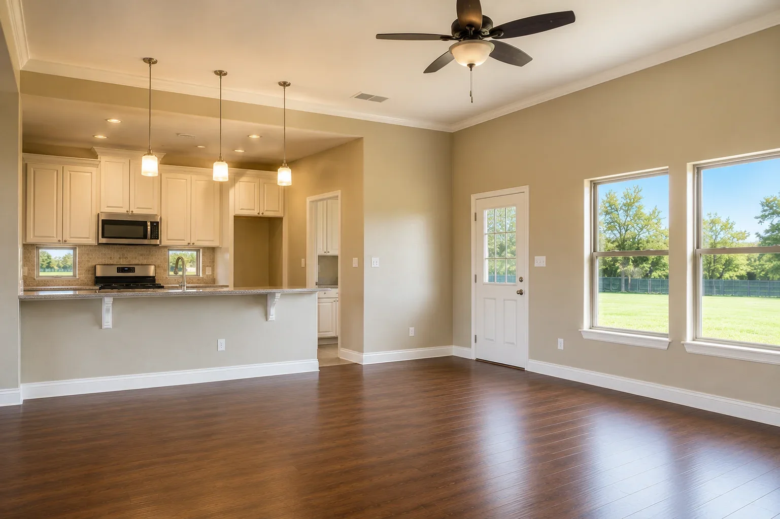 Open concept kitchen and living room with cream cabinets, granite counters, and hardwood floors