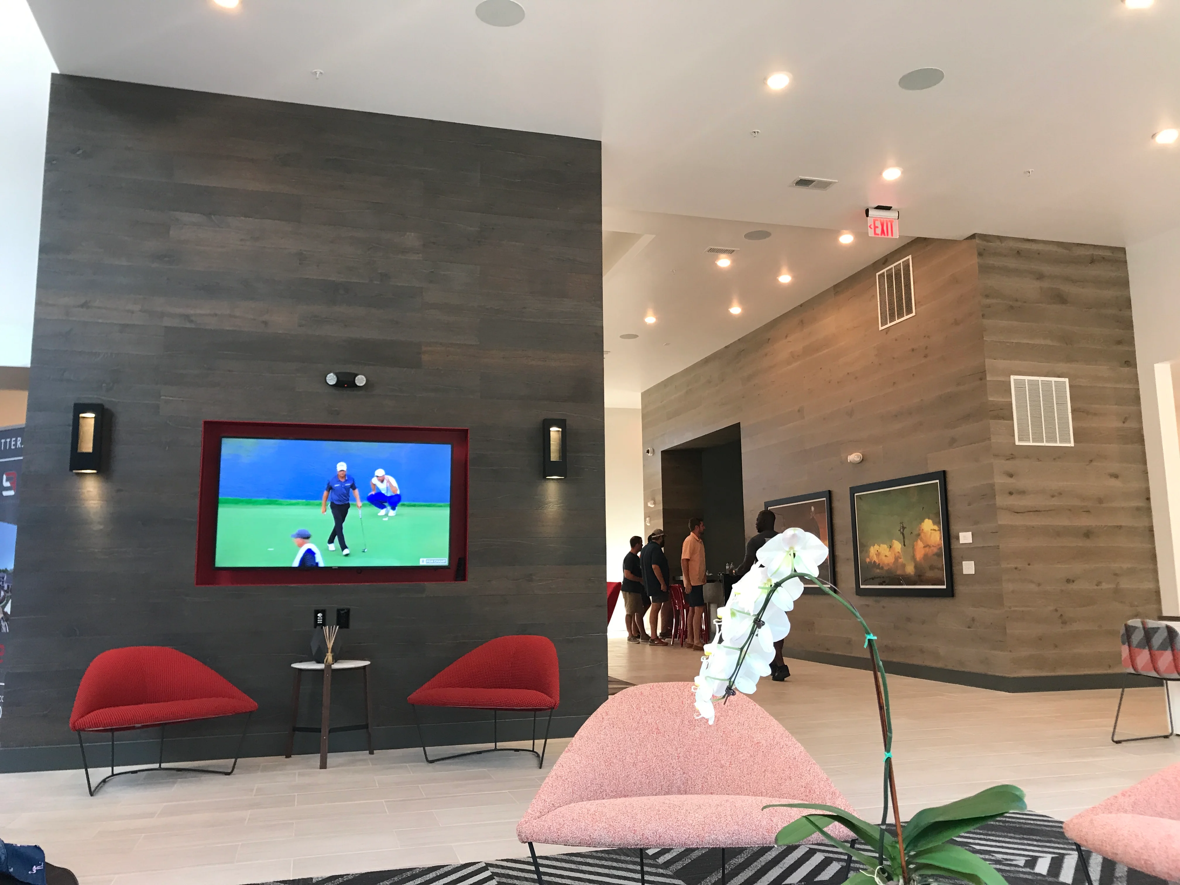 Modern commercial interior with dark wood accent wall, mounted TV, and contemporary seating