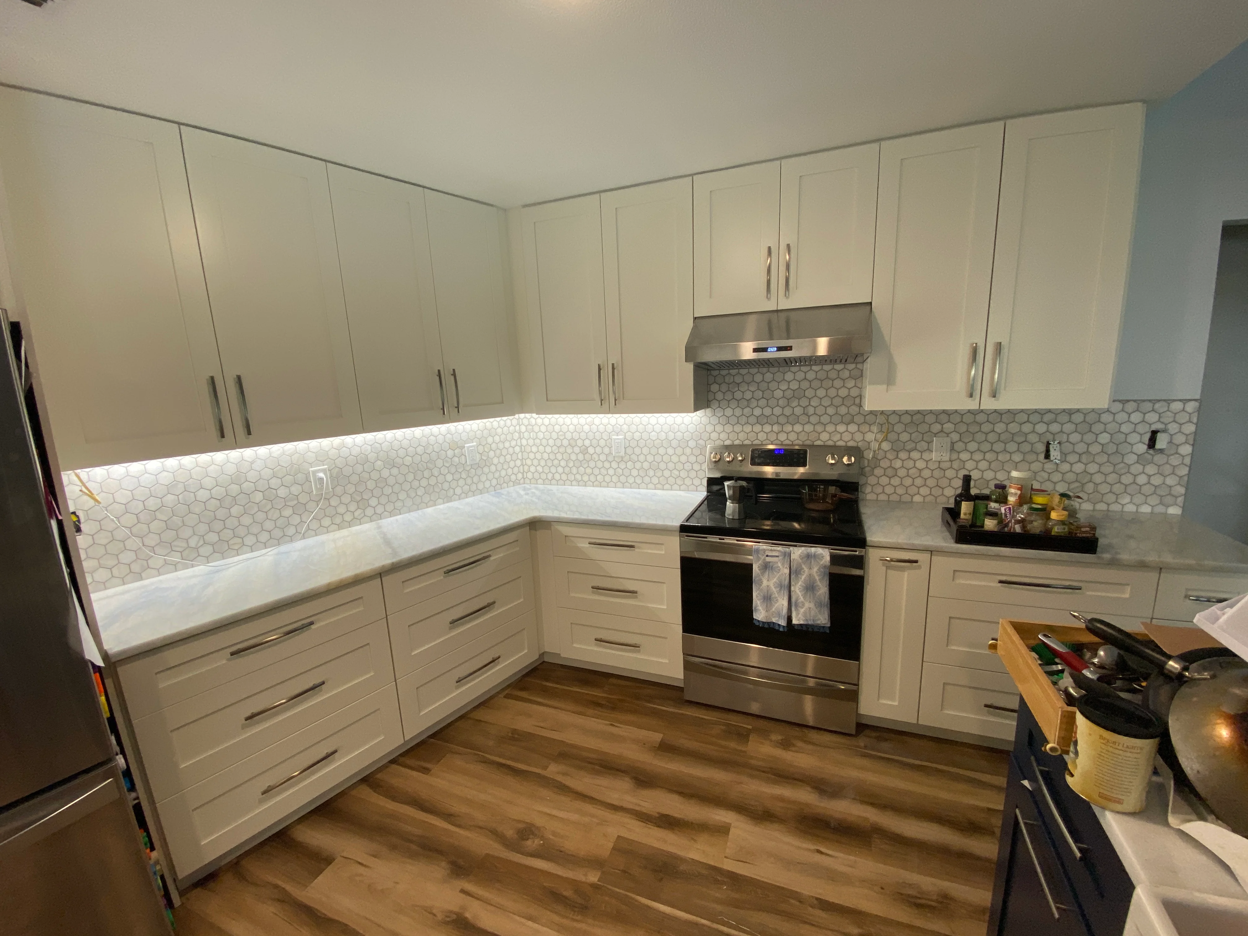 Modern kitchen with white cabinets, hexagonal tile backsplash, and stainless steel appliances