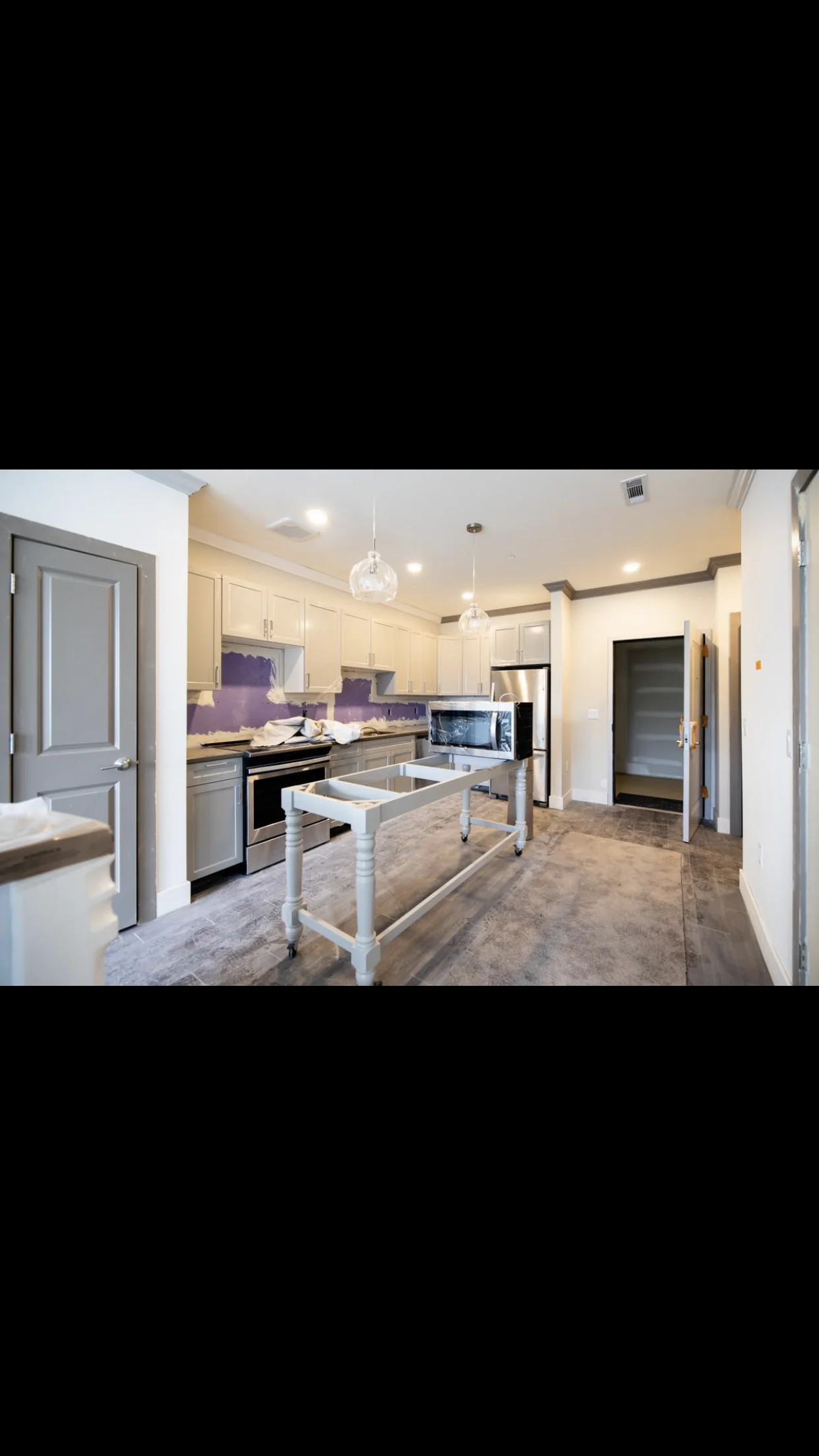 Modern kitchen with cream cabinets, purple backsplash, stainless steel appliances, and white island