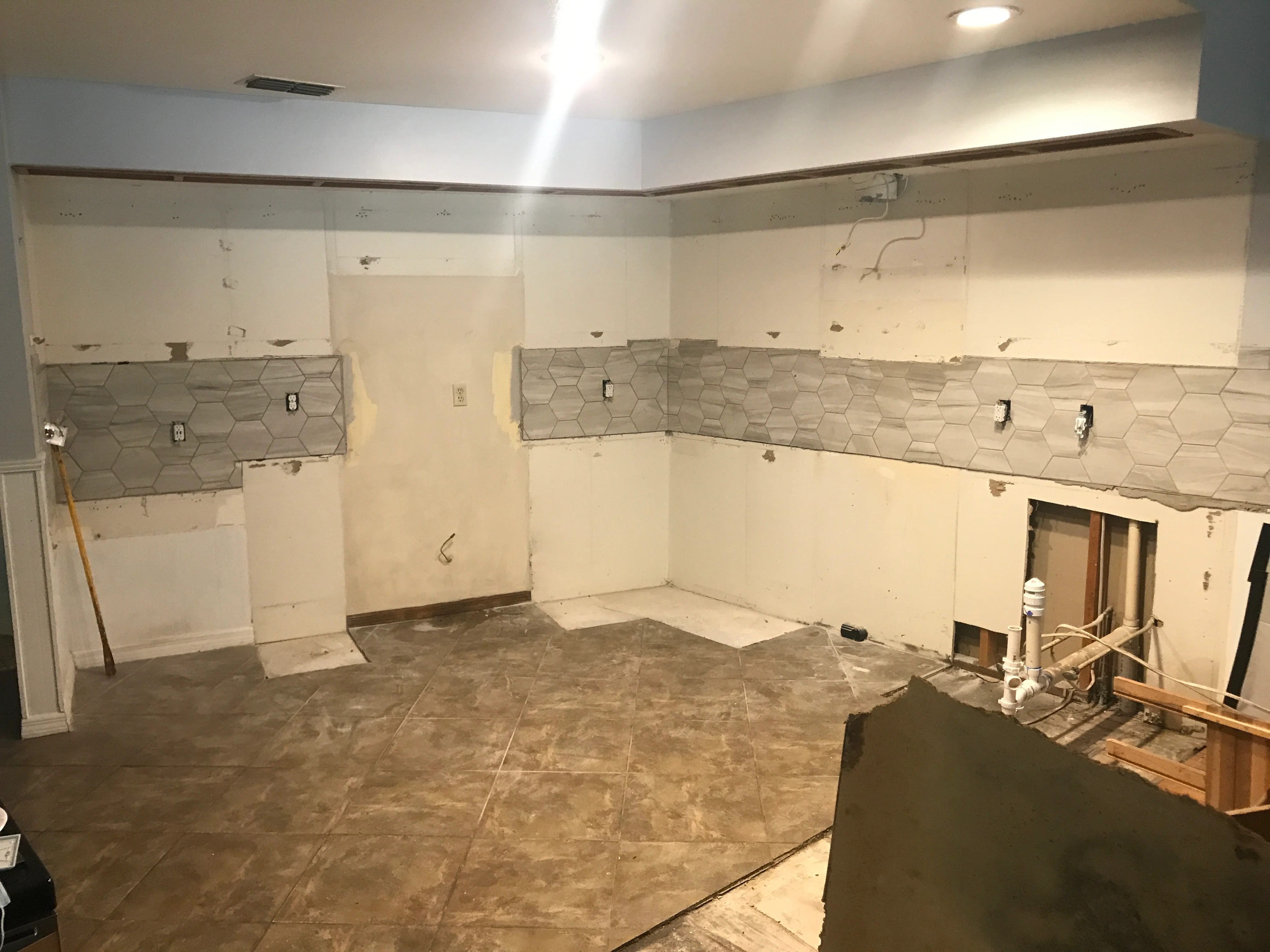 Bathroom remodel mid-construction with hexagonal tile, drywall, and plumbing fixtures