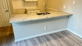Modern kitchen island with granite countertop, white cabinets, and stainless steel sink