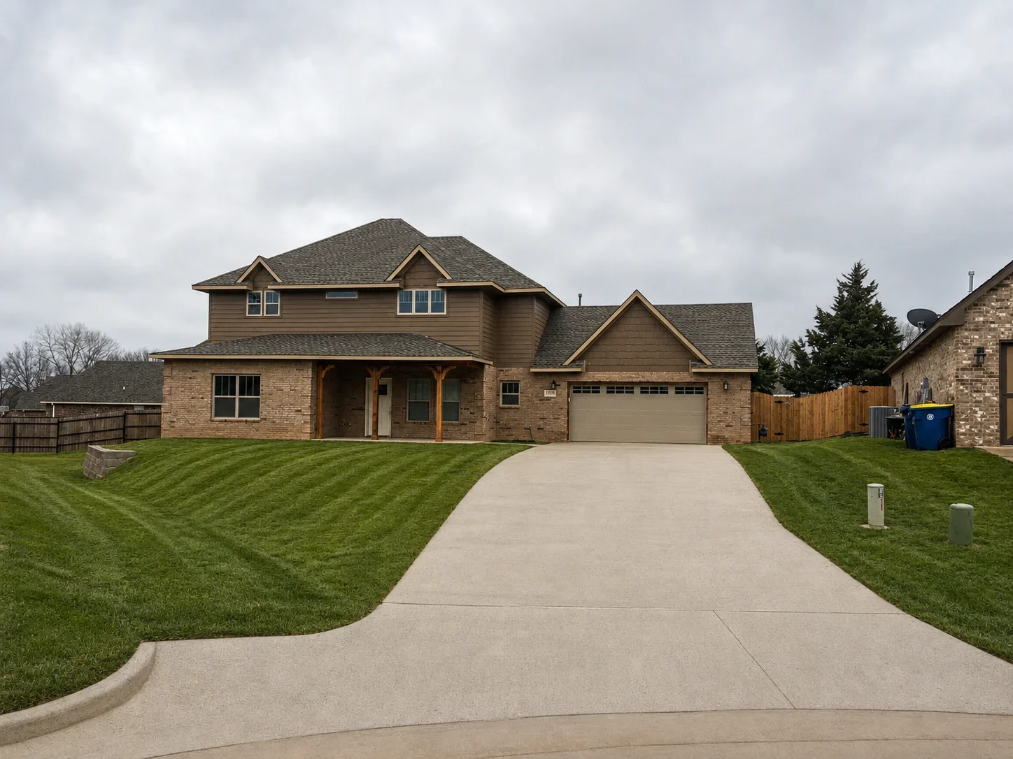 Two-story brick home with garage, concrete driveway, and manicured lawn