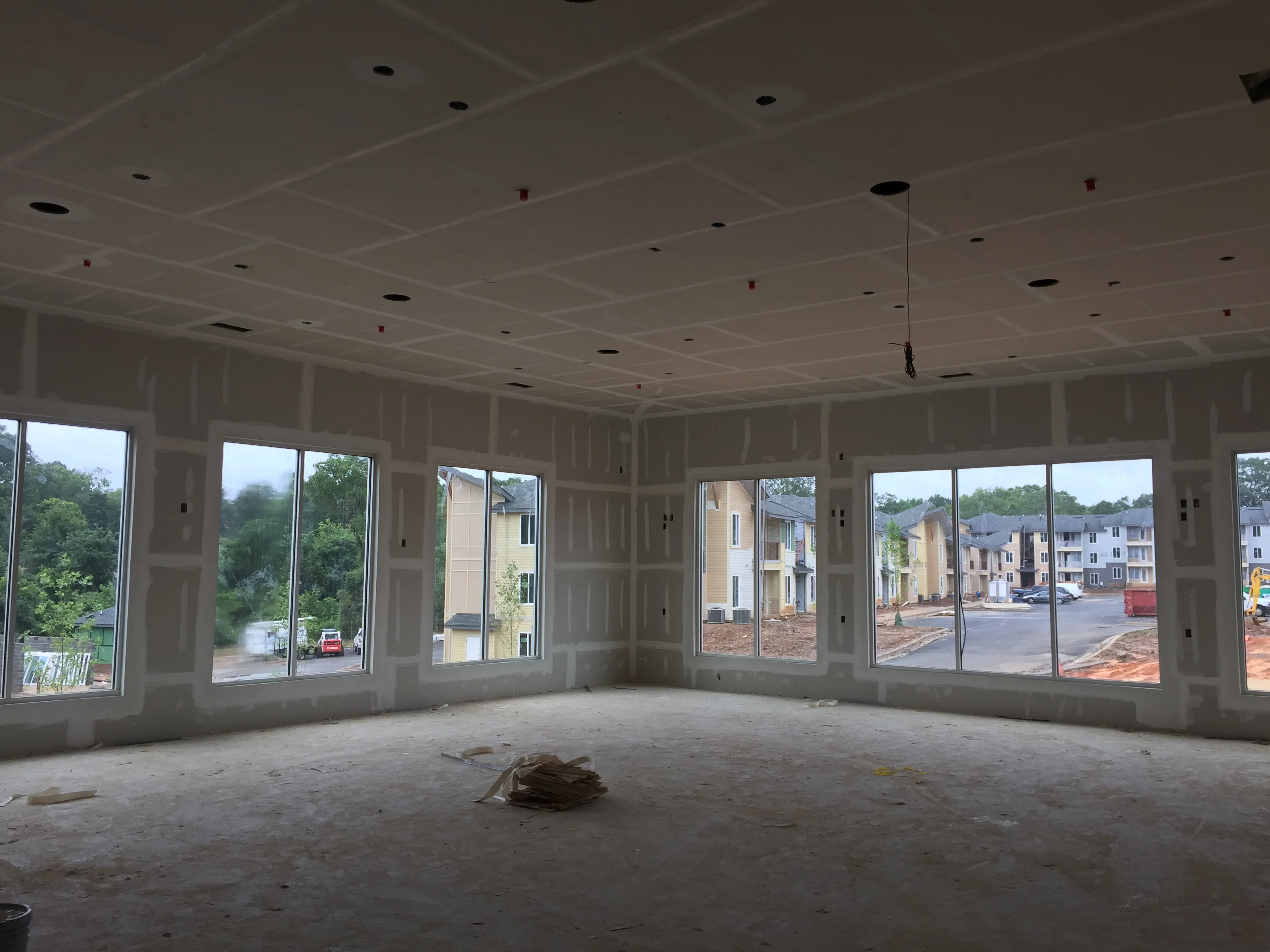 Interior construction space with drywall, framing, recessed lights, and large windows