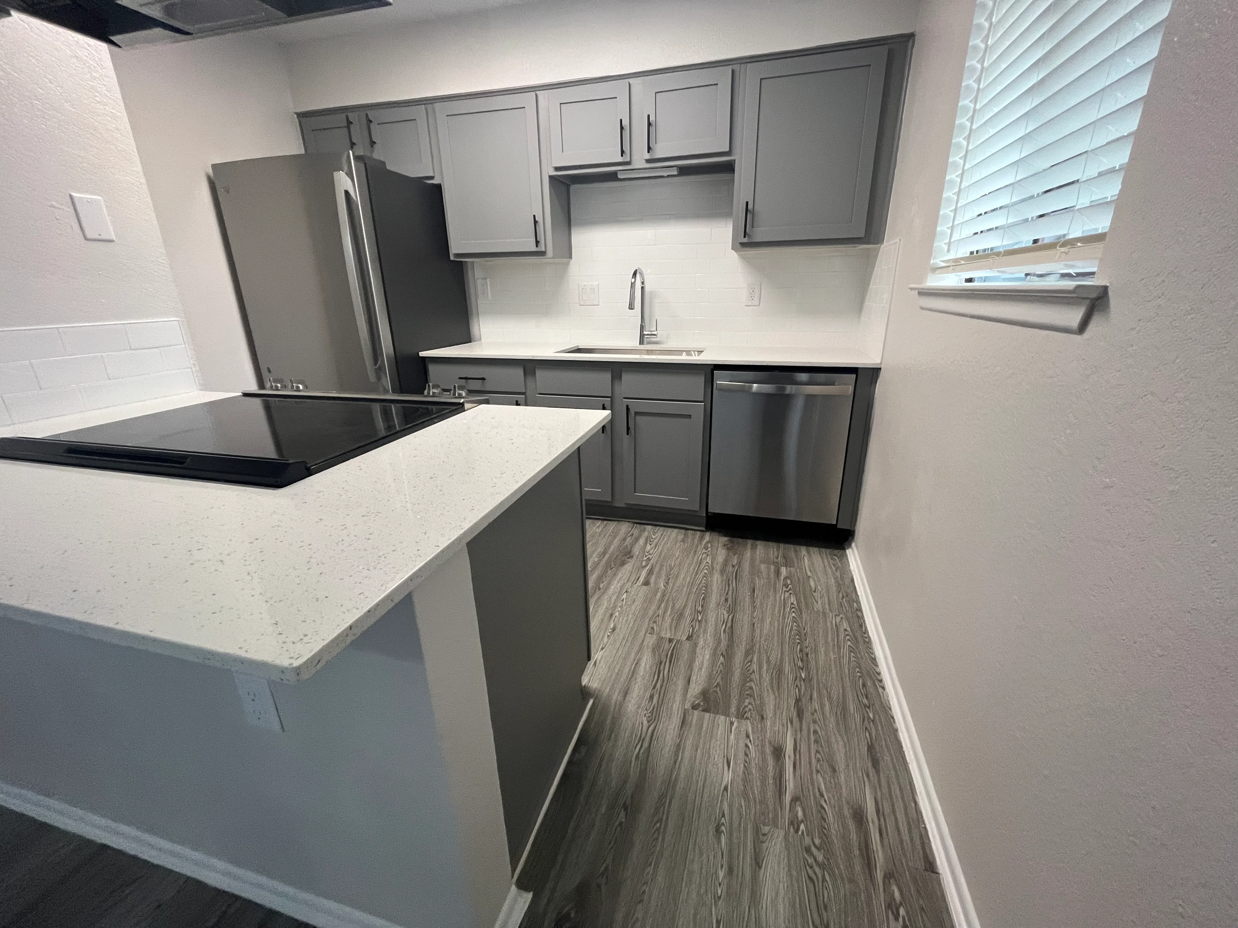 Modern kitchen with gray cabinets, white quartz countertops, island, and stainless steel appliances