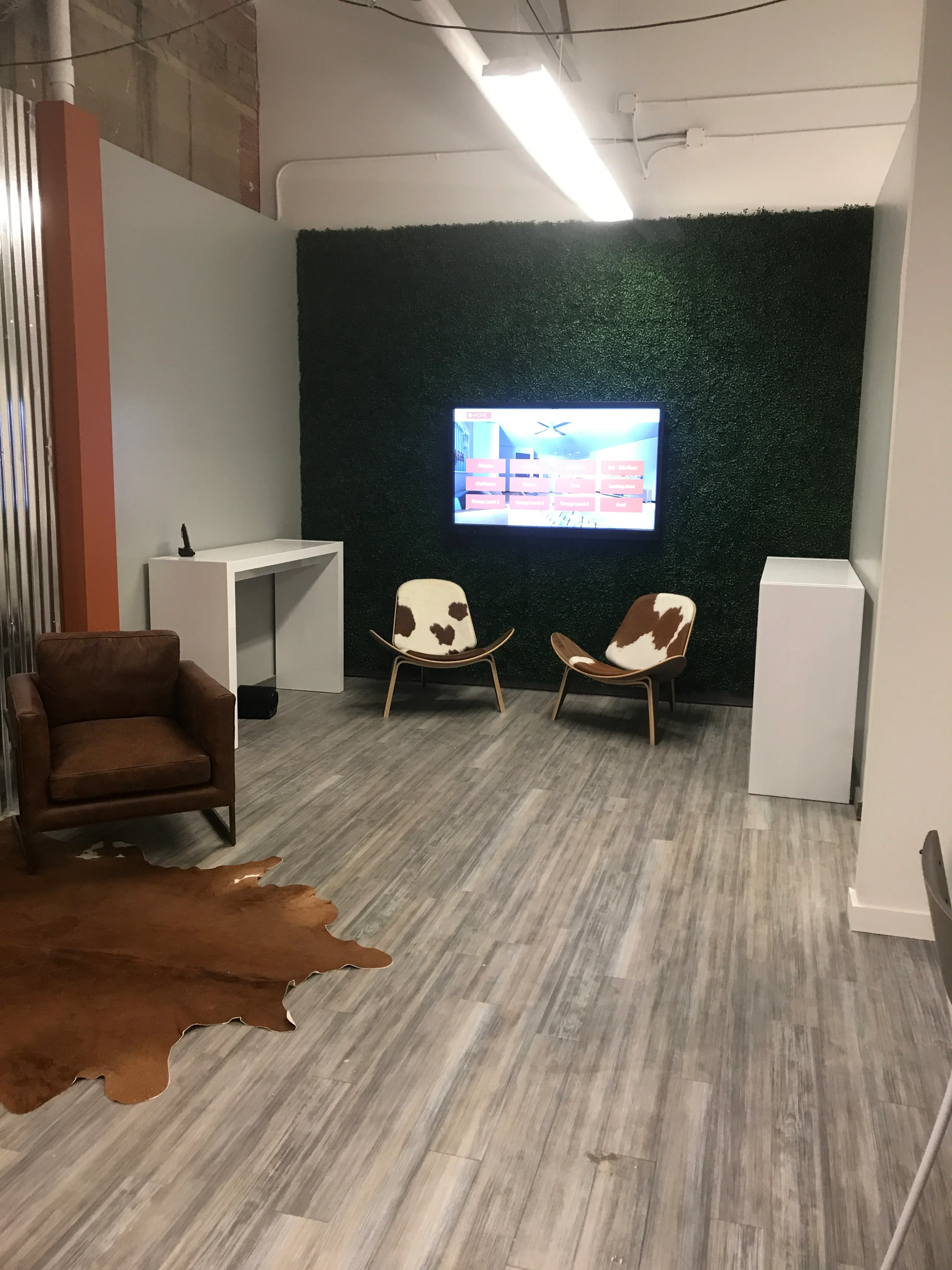 Modern commercial interior with green accent wall, white cabinetry, and contemporary seating