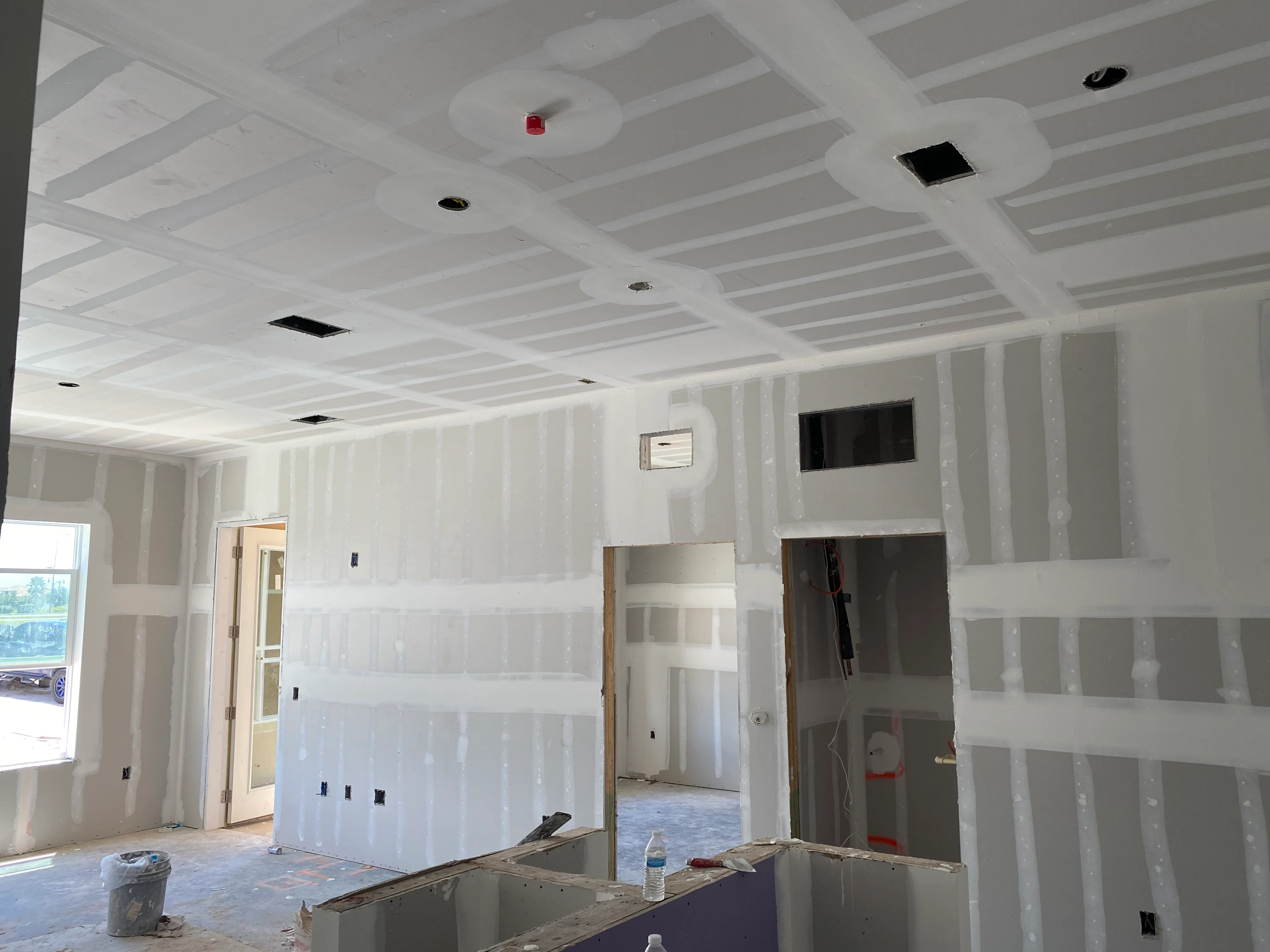 Commercial interior with metal stud framing, drywall installation, and recessed lighting fixtures