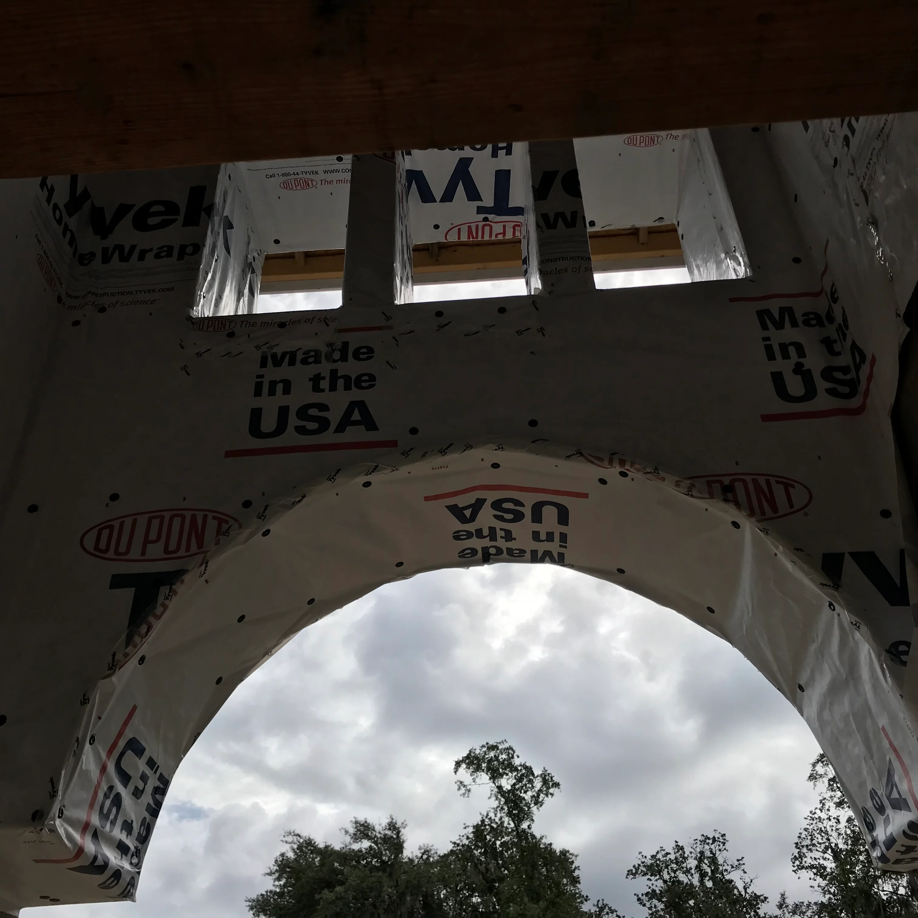 Exterior house wrap installation on residential framing with window openings and protective coverings