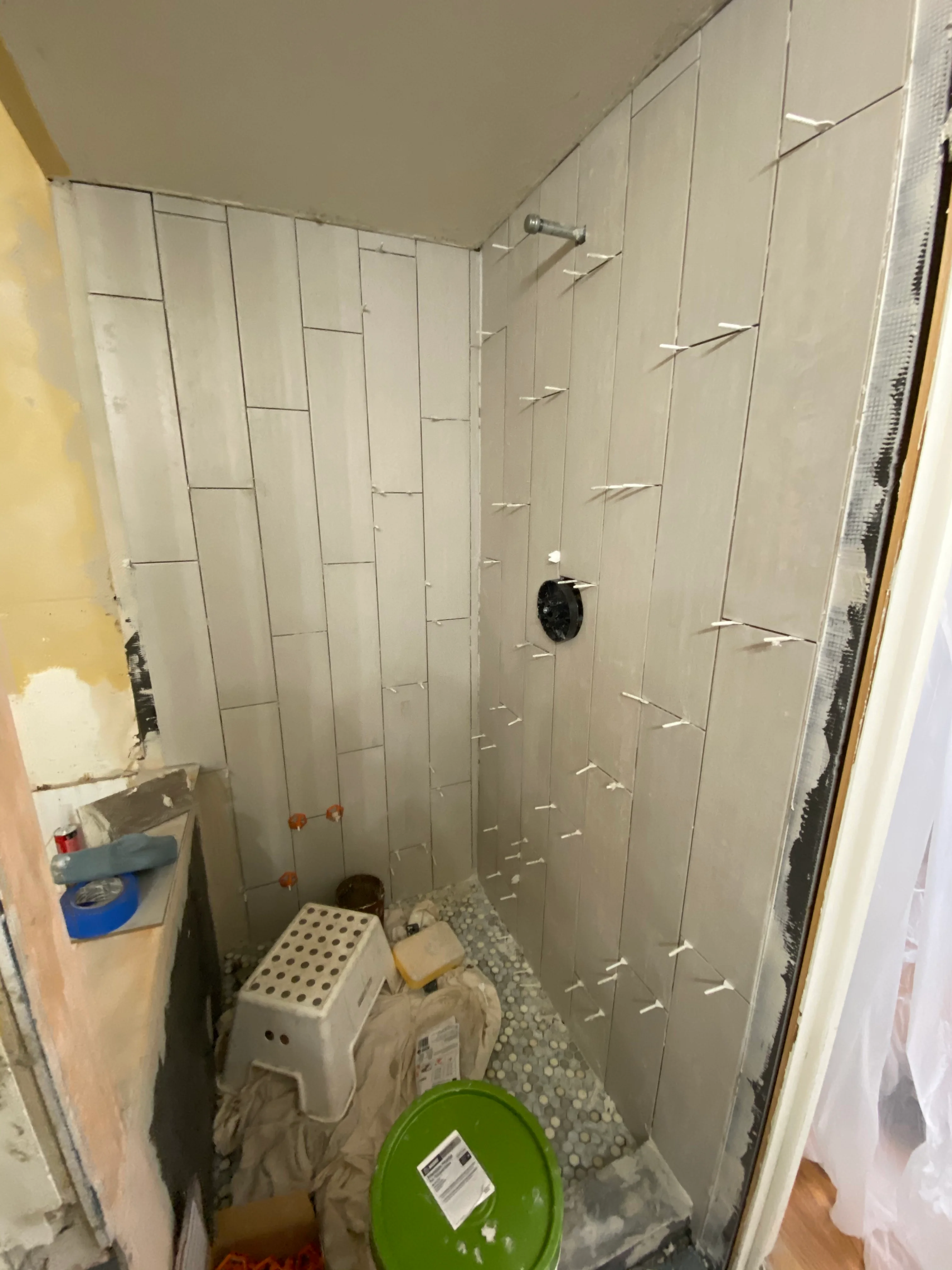Bathroom shower renovation with vertical subway tile walls and penny tile floor in progress