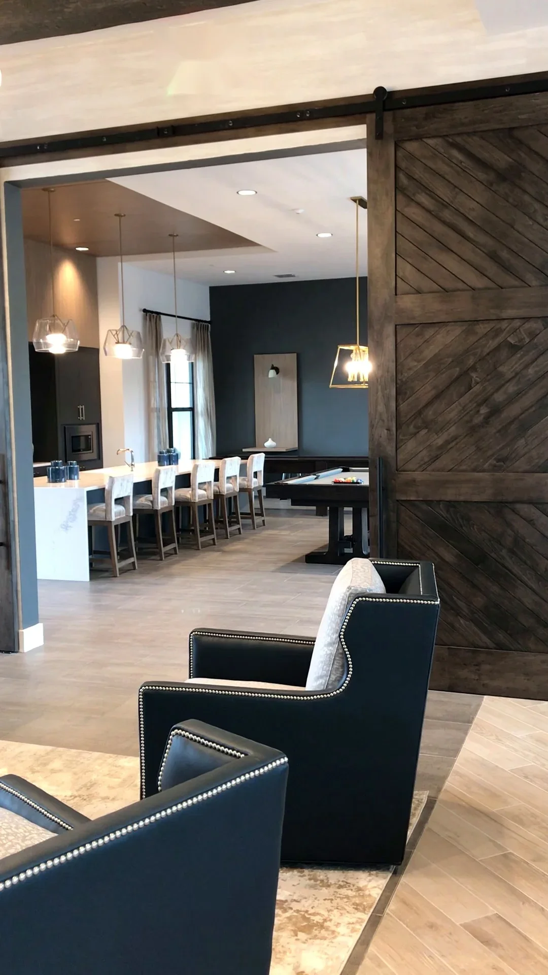 Modern kitchen with marble island, dark accent wall, and sliding barn door entry