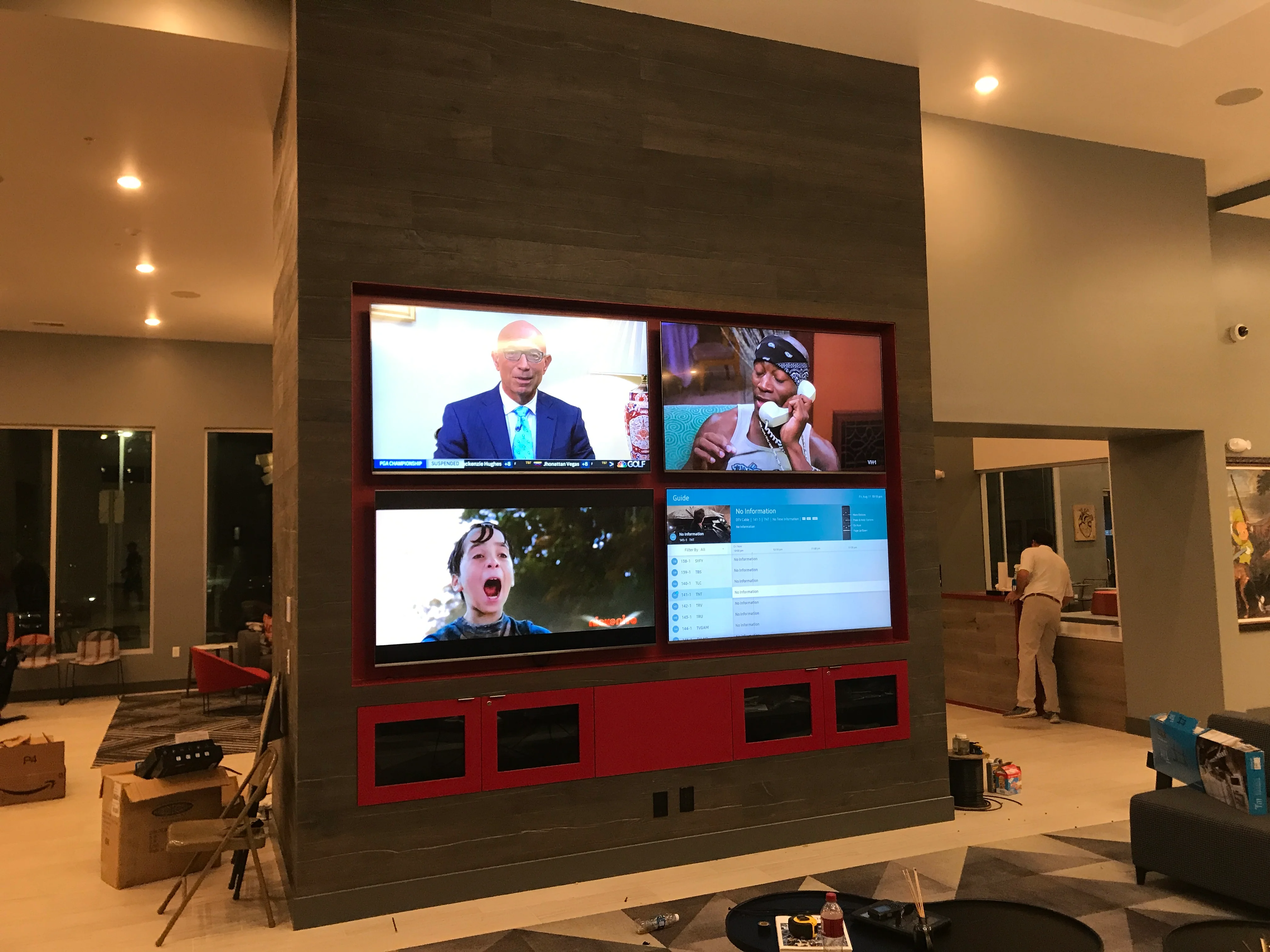 Custom media wall with four integrated screens and red cabinetry in modern home theater