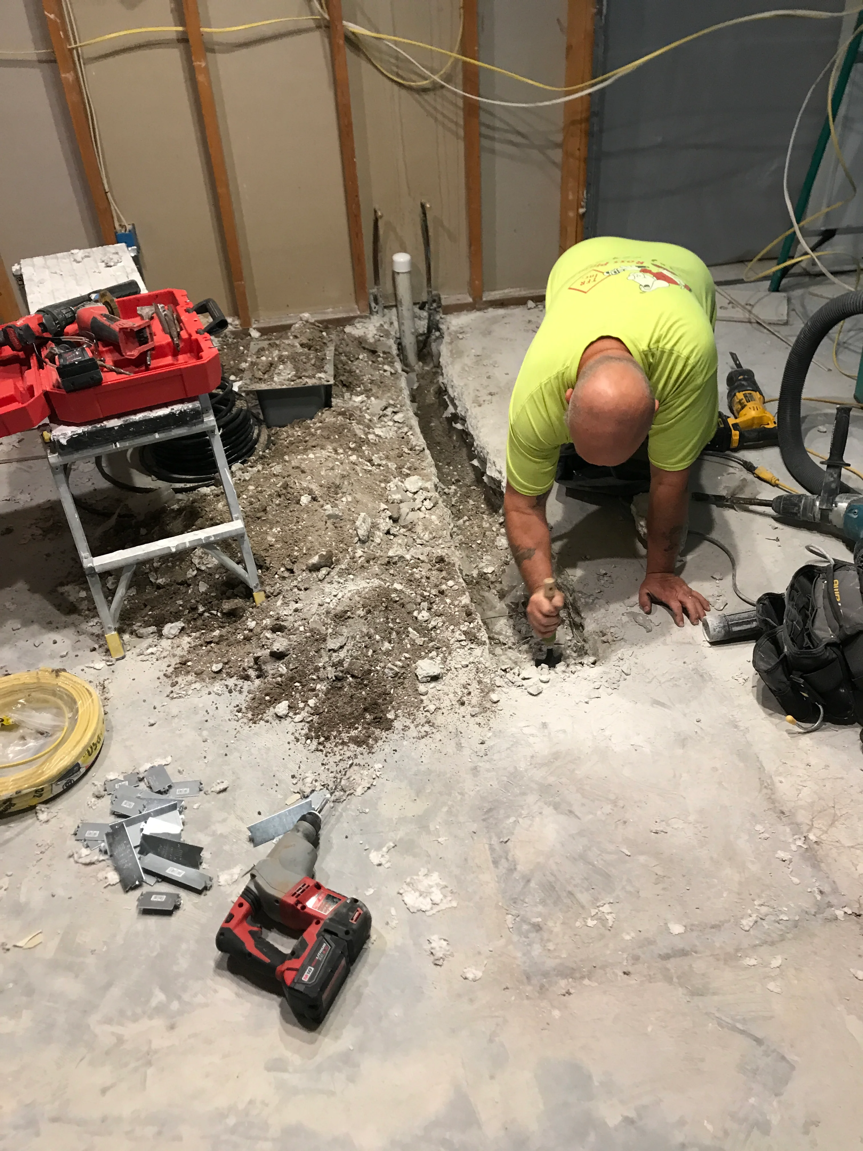 Worker in safety vest removing concrete flooring during interior demolition project
